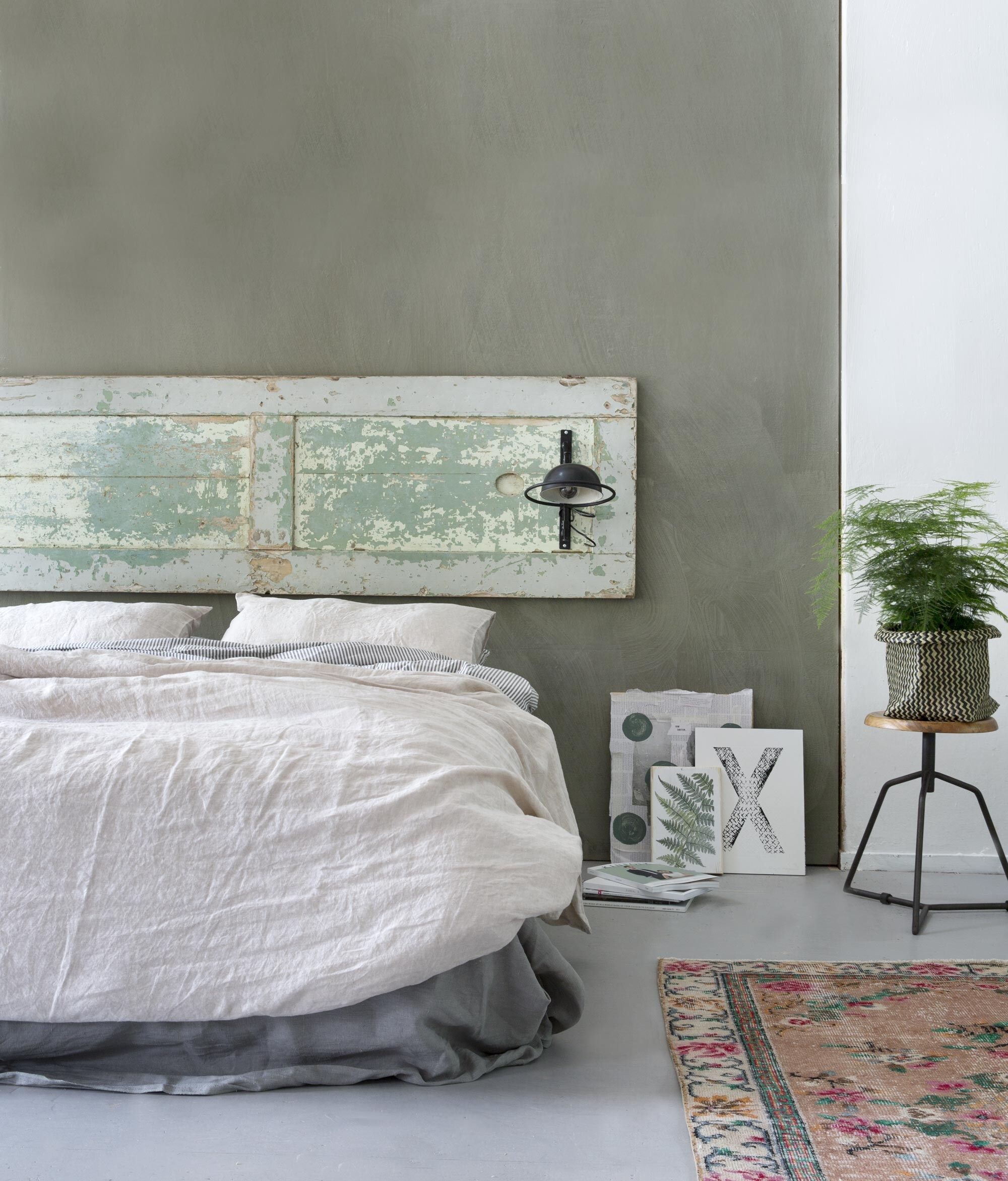Deur (). Verf op de muur: Olive van Bauwerk lime paint ().  (Bodilson). Dekbedovertrek zwart-wit  (Ikea).  over voeteneinde matras Aina (Ikea). Linnen dekbed- overtrek naturel, linnen kussenhoezen naturel (). Vloerkleed (). Kunstwerken tegen muur: krantencollage op hout van Marjon Hoogervorst, letter X van Marjon Hoogervorst (). Botanische afbeelding op hout ().  (Basiclabel).  Magga (Ikea).