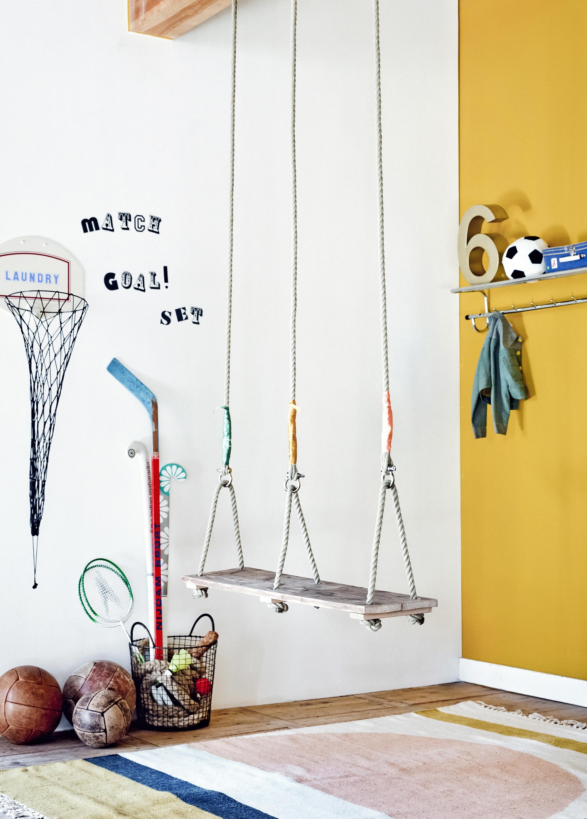 Muurverf Goud 1573-Y10R per 2,5 liter vanaf (). Vloerkleed van Ferm Living (). Basketbalnet voor de was, (). , Badmintonrackets met shuttles ,  (Ikea). Vintage medicijnballen per stuk, klimtouw (). IJzeren mand (). IJshockeystick, kapstok (). Hockeysticks vanaf (). Cijfer (). Koffertje (). Vintage jasje ().