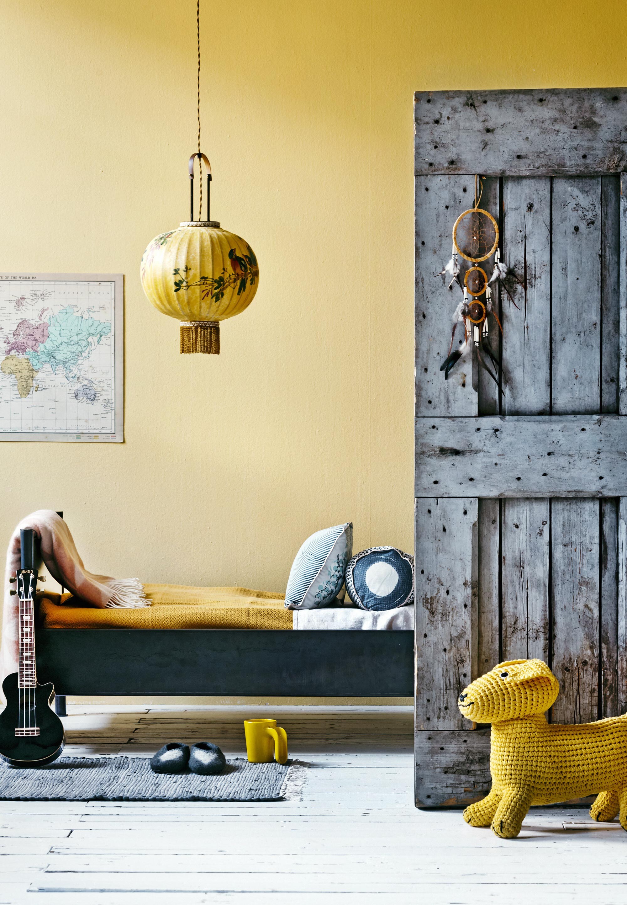 Eikenhouten vloerdelen, wit geverfd per m² (). Muurverf F6.25.80 per 2,5 liter vanaf ().  (Ikea). Met de hand geschilderde lamp (). Stalen bed met matte coating van Anouk B 150×70 cm (). Gele ledikantdeken van Imps &amp; Elfs, beker ().  (Ikea). Plaid (). Rond kussen sierkussen Rabbit 30×50 cm (). Vloerkleed (). Deur vanaf (). Dromen-vanger € 1,- (). Gele gehaakte hond van Anne-Claire Petit (). Sloffen (). De gitaar is privébezit.