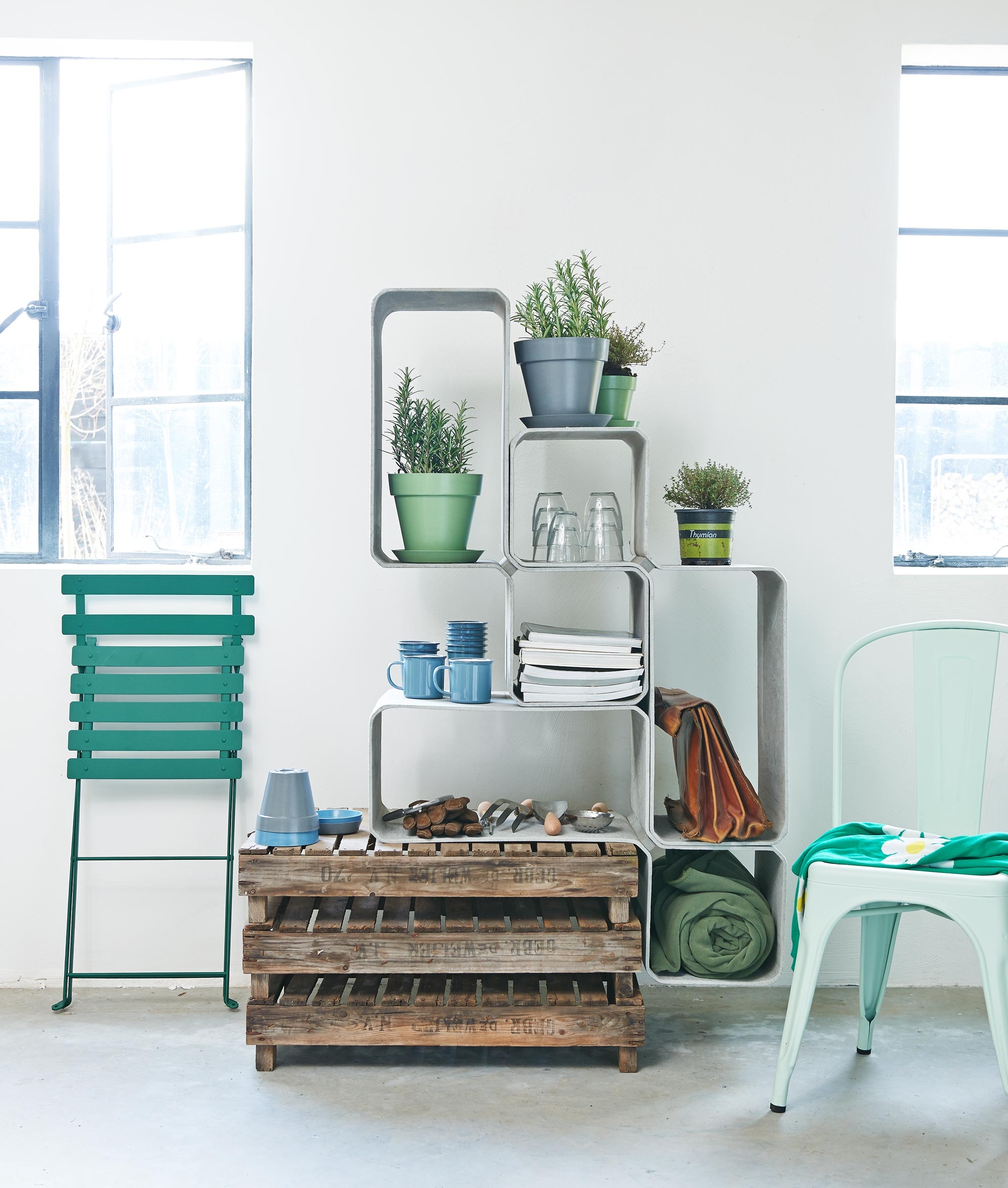 Tetris modulaire elementen van Eternit, leger-groene kruk van Chaises Nicolle, tuingereedschap Fork, Trowel en Potting sieve van Sophie Conran, leger-groene plaid, Gigogne glazen per set van 6, emaillen bekers zonder oor, bekers met oor, groene bistrostoel van Fermob links, mint-groene stoel Tolix Chaise A (Extra Vert). Bamboe potten S in een set van drie met onderschaal (Hema). De overige spullen zijn privébezit. In de potjes zit rozemarijn.