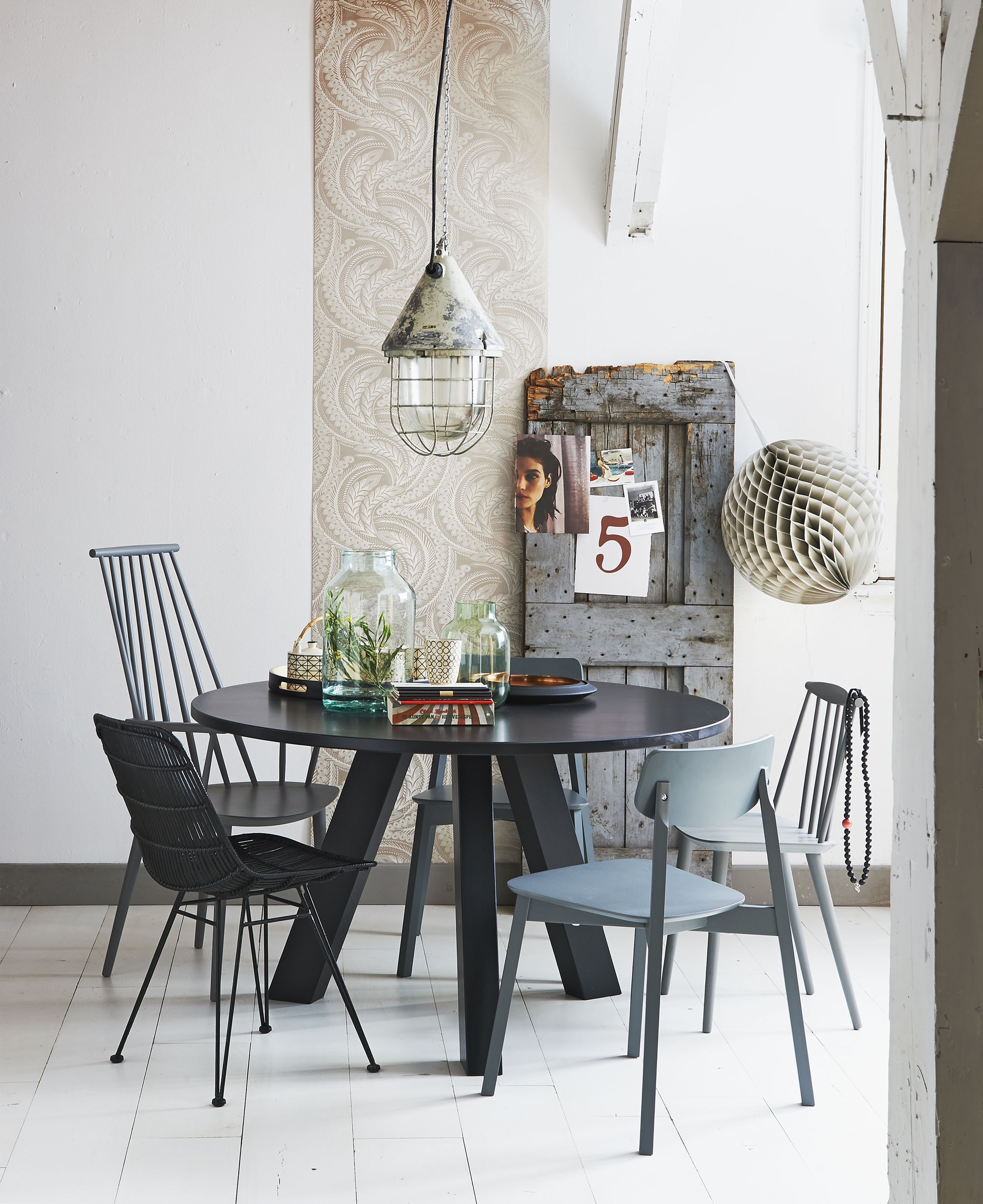 Tafel Circle van bepurehome Ø 130 cm, groene glazen vaas House Doctor, zwart dienblad met koper- kleurige binnenkant Sola (vtwonen.nl). Hoge spijlenstoel, lage spijlenstoel (Hay). Zwarte rotan stoel (HK Living). Grijze stoelen Stip (Basiclabel). Papieren bol Visionär (Ikea). Industriële lamp Komodo Dragon (Blom &amp; Blom). Transparante vaas (Van Dijk &amp; Ko). Bekers per stuk, theepot, dienblad (Nijhof).