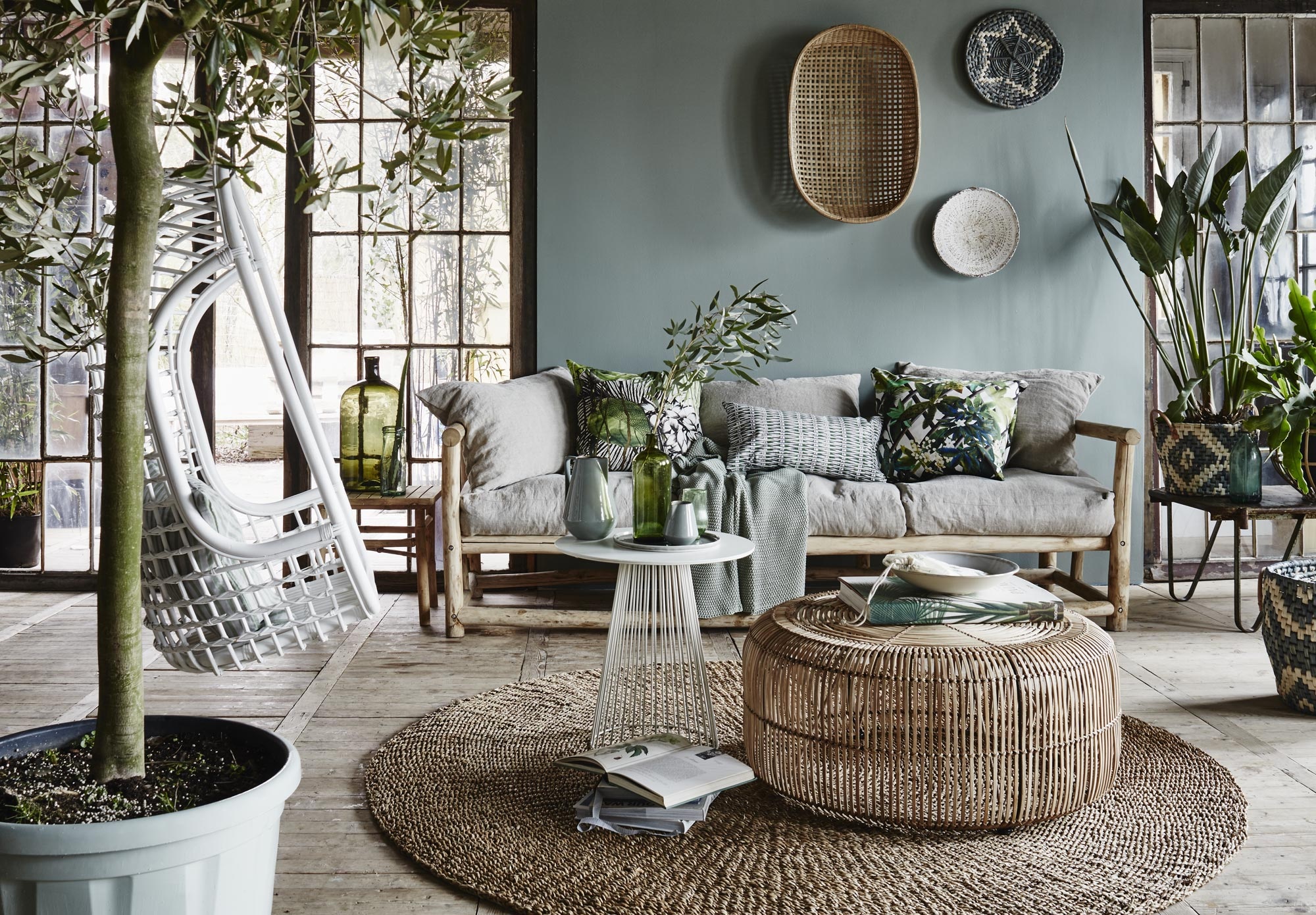 Driezitsbank inclusief zeven rug- en zitkussens (). Zachtgroene plaid in grof weefsel (). Decoratiekussens van Christian Lacroix, Jardin Exo’chic Rainette, Barbade Malachite en Canopy Malachite (). Bamboe bijzettafel van Tine K Home (). Groene flesvaas erop (). Rechts: tafel Krosno ().  van Bloomingville (vtwonen.nl). Ovale mand aan de muur van Tine K Home vanaf(). Mand met ster (). Witte schaal (). Op bijzettafels: flesje(). Kan en melkkan van Ferm Living (). Groen glas (). Bord(). Boek Palms (). Schaal ().  van HK Living (vtwonen.nl). Witte bistrotafel Garbo (). Rotan salontafel (). Vloerkleed van Bloomingville € 159,- (). Serredeuren (). De muur is geschilderd in Castel Gray nr. 92, Estate emulsion ().