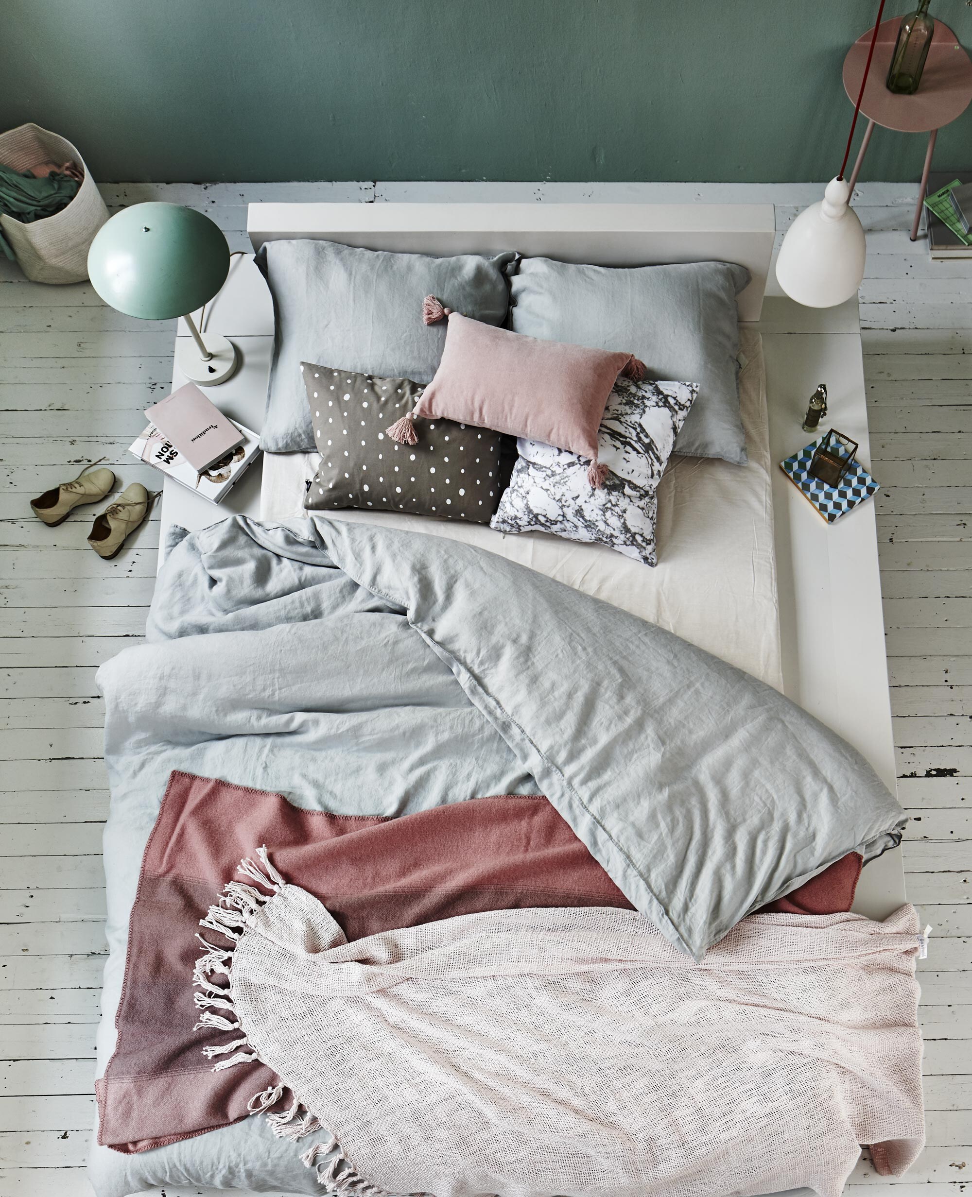 Podiumbed met brede ombouw op maat gemaakt (). Linnen dekbedovertrek 220×240 cm (). Plaid onderop van Normann Copenhagen (). Bovenste plaid in zachtroze (). Vintage mintgroene lamp (). Keramieken hanglamp (). Roze fluwelen kussen (), kussen met stippen van Ferm Living 40×60 cm (), kussen met marmerprint (). Glazen doosje (). Huisparfum (). Notitieboekje (). Witte stoffen mand (), bijzettafel in roze van Menu (). Vaasje (). Muurverf: Aquamarine 138 van Little Greene in de kwaliteit Absolute matt ().