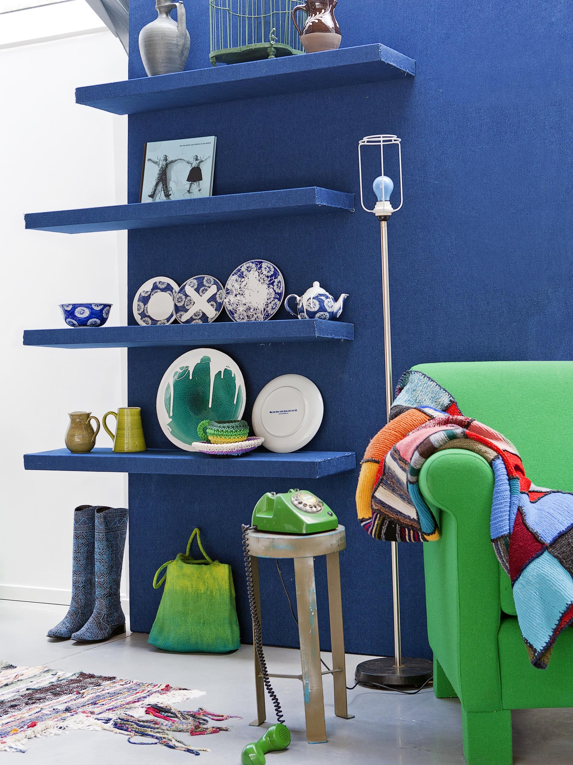 Lack planken 110x26x2 cm (). Jeansblauwe stof Blue Print (). Groene fauteuil Marie (). Patchwork plaid (). Krukje (vtwonen.nl). Vintage telefoon (). Voddenkleed (). Laarzen, vilten tas Zsófia Marx (). Schemerlamp, met kap die hier is weggelaten (). Op de planken van onder naar boven en van links naar rechts: bruin kannetje (). Groen kannetje (). Groen bord, hier met witte verf bewerkt (). Gehaakte kop-en-schotel voor een set van theepot en twee koppen (). Bord, kommetje, bordjes vanaf, theepotje (). Boek Het meubilair van Eames (). Kruik (). Vogelkooi (vtwonen.nl). Kannetje ().