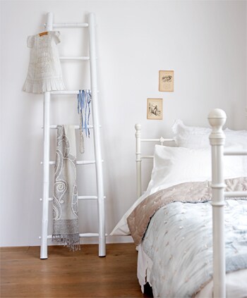 beeld vtwonen Deze houten ladder is overal in huis te gebruiken. In de badkamer hang je er handdoeken overheen, of je showt hem zoals hier afgebeeld: in de slaapkamer met allerlei mooie items eraan. Het bed met dekbed, kussen en hoeslaken zijn van Ikea, de plaid en de shawl van Lifestyle. Fotografie Simone de Geus.