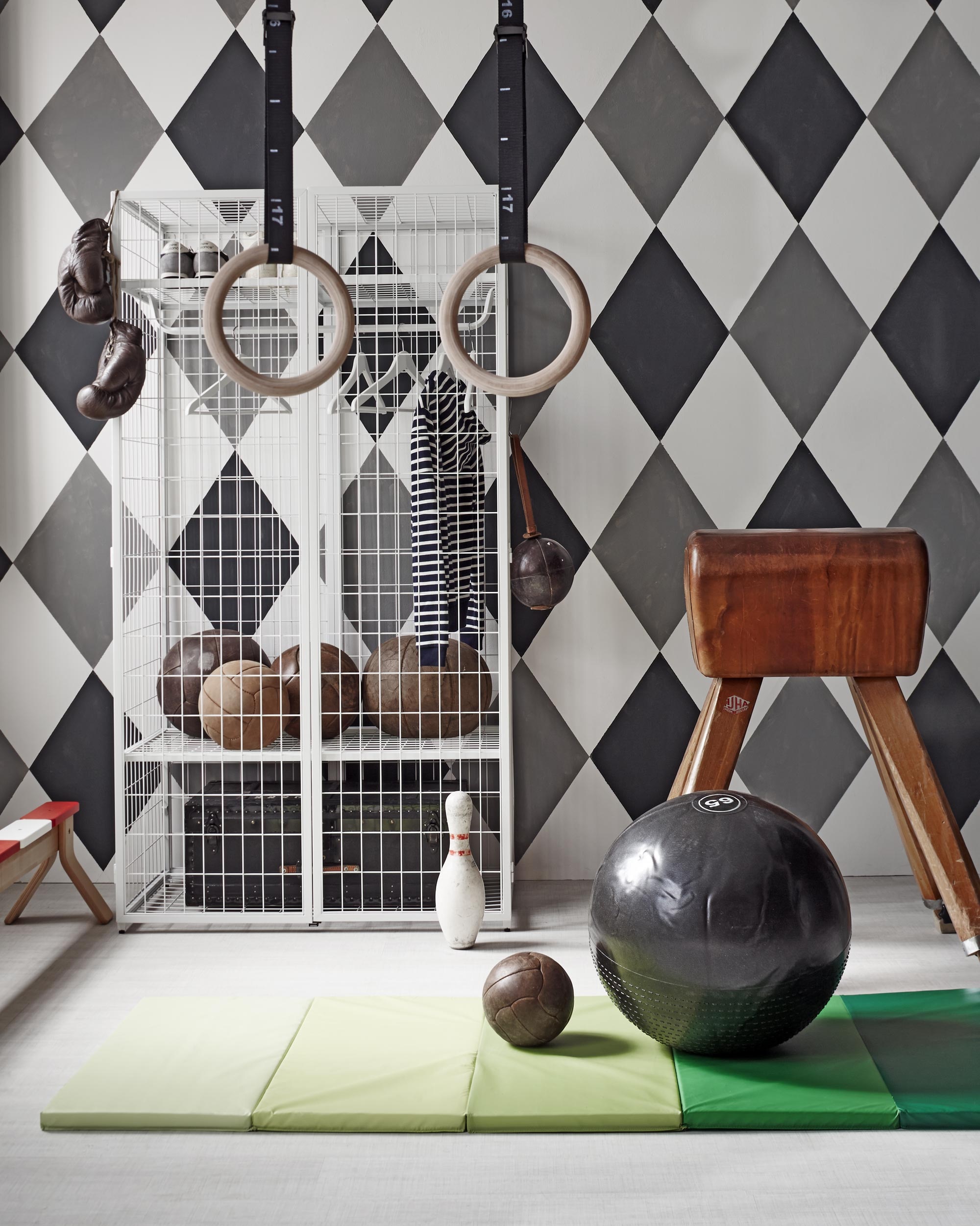 Kast Ikea PS 2014, gymmat Plufsig, evenwichtsbank Ikea PS 2014, set kledinghangers Bumerang (). Oude gymbok (). Houten gymringen MP122 en gymbal van Adidas Ø 65 cm (). Oude leren gymballen en leren bokshandschoen (). Leren trainingsbal met leren lus en kegel (). Zwarte kist in kast (). Het dessin is geschilderd in muurverf grijs Plummett 272, zwart Off-Black 57, wit Strong White 2001 (). Gestreept vest (). Gympen New Balance ().