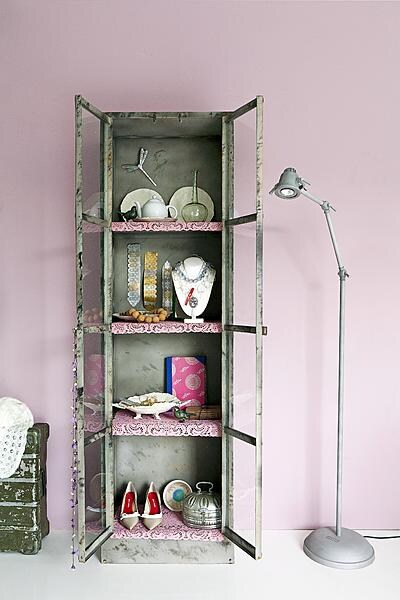 beeld vtwonen Kostbaarheden in een donker sieradenkistje bewaren mag dan veilig zijn, decoratief en creatief is het allerminst. Deze ijzeren vitrine schreeuwt om sierlijk dierbaar bezit. Dankzij de toevoeging van roze placemats krijgt de ruige kast de elegante uitstraling van een minimuseum.\n