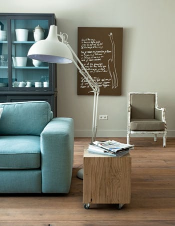 beeld vtwonen Kleur is een goed middel om basic houten vloeren een oppepper te geven. In deze woonkamer is gekozen voor lichtblauw. Een bescheiden kleur die toch dat beetje extra geeft. Ook leuk: de XL-bureaulamp. Fotografie Dennis Brandsma.
