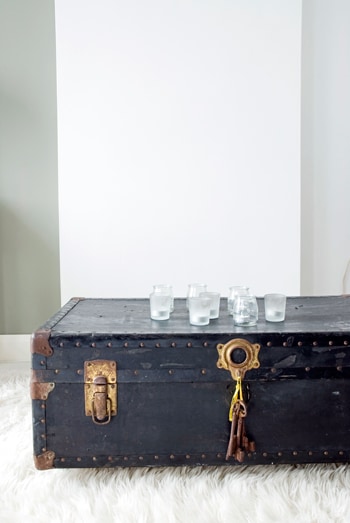 beeld vtwonen Deze oude kist dient als salontafel. Op de kist staan kleine yoghurtglazen, mat en doorzichtig door elkaar. Fotografie Jantien de Bood.