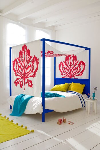 beeld vtwonen Hemels slapen en ontwaken in blauw dat wel fluorescerend lijkt. In een hemelbed dat net even anders, stoer en uitdagend is. Hier geen romantische aankleding, maar met een uitgesproken bladdessin in knallend rood. Fotografie Anna de Leeuw.