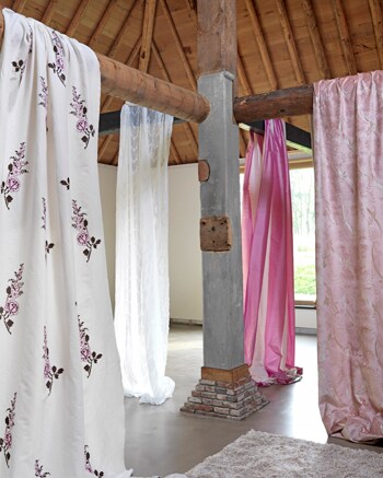 beeld vtwonen Deze frisse zomerse bloemetjesgordijnen geven je huis in een mum van tijd een zomerse uitstraling. Deze gordijnen zijn van Chivasso. Van links naar rechts: Cottage garden, katoen met daarop een bloem geborduurd in vier kleuren. Vintage, witte transparante stof met daarin een wit motief. Voyage 100% zijde met brede glanzende banen. Fountain roze glanzende stof met guirlandes.