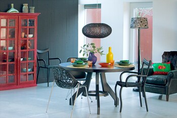 beeld vtwonen Kies de tafel, stoelen en lamp met zorg en je eethoek zit als gegoten. Ronde zwarte tafel Popov (Pol's Potten). Lamp (Nijhof), opengewerkte stoel Eames (Loods 5), stoel met rieten zitting (Pol's Potten). De blauwe vaas is van Sjakies. Fotografie Bob Eshuis.