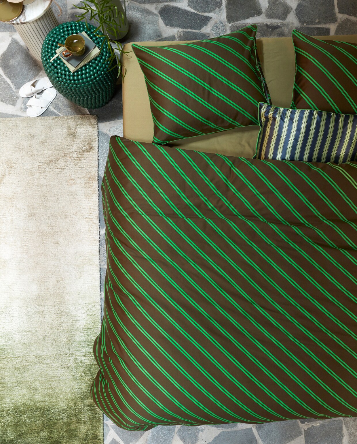 Katoensatijnen dekbedovertrek Diagonal, 140×200/220 cm € 79,95, 200×200/220 cm € 149,95, 240×200/220 cm € 159,95, 260×200/220 cm € 179,95. Satijnen kussen met bies Pyjamas, 40×60 cm € 39,95. M.m.v. made.com (vloerkleed), nordal.eu (marmeren bijzettafel Erie), polspotten.com (groene bijzettafel Dot Stool, groene metalen vaas Roman), paviljoennoord.com (mok). Overig privébezit. vtwonen 13-2022 | productie Tanja Saarberg | styling Danielle Verheul | fotografie Richard Smit