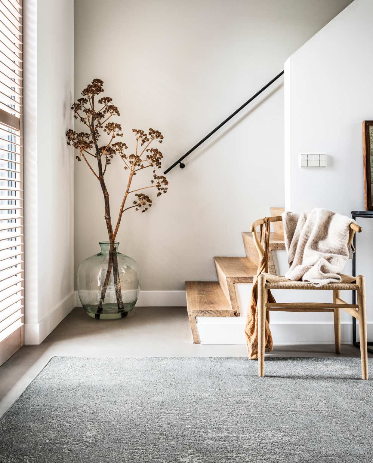 Vloerkleed Stonewashed Zinc, ook in Pebble en Washed Black, op maat gemaakt met gefestonneerde rand, 200×300 cm. M.m.v. misterdesign.nl (Wishbone Chair Hans J. Wegner), hetkabinet.nl (zwarte bijzettafel), fishonthemoon.com (tas), stories.com (vest), overig privébezit. productie Tanja Saarberg | styling Kim van Rossenberg | fotografie Sjoerd Eijckmans