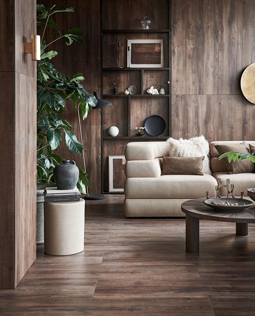 Laminaat XL Collar warm bruin, lamel 138×32,6×0,8 cm met groef, inhoud pak5 stuks voor 2,25 m², per m² € 27,99.M.m.v. couleurlocale.eu (beige bijzettafel Pawn van Serax), vtwonen.nl (gouden wandlamp Trio Cleo, houten ronde salontafel Post van Ferm Living), goeds.nl (vloerlamp brass met matzwarte kap van Gubi, goudkleurig wandobject, fauteuil Co van Menu), studio-henk.nl (bank Layer Sofa), zarahome.com (plaid, kussens, zwart bord, keramieken bol, donkergroene vaas, marmeren schaaltje), hm.com (goudkleurige kandelaar, beige vaasje), casagitane.com (bruine schaal), mooswillemsen.com (art op paper in lijst No 166 / No 169), waterdrinker.nl (planten en grote bloempot), vestingh.nl (verf planken kast Peppery Black No. 71). vtwonen 03-2022 | styling Kim van Rossenberg | fotografie Sjoerd Eickmans