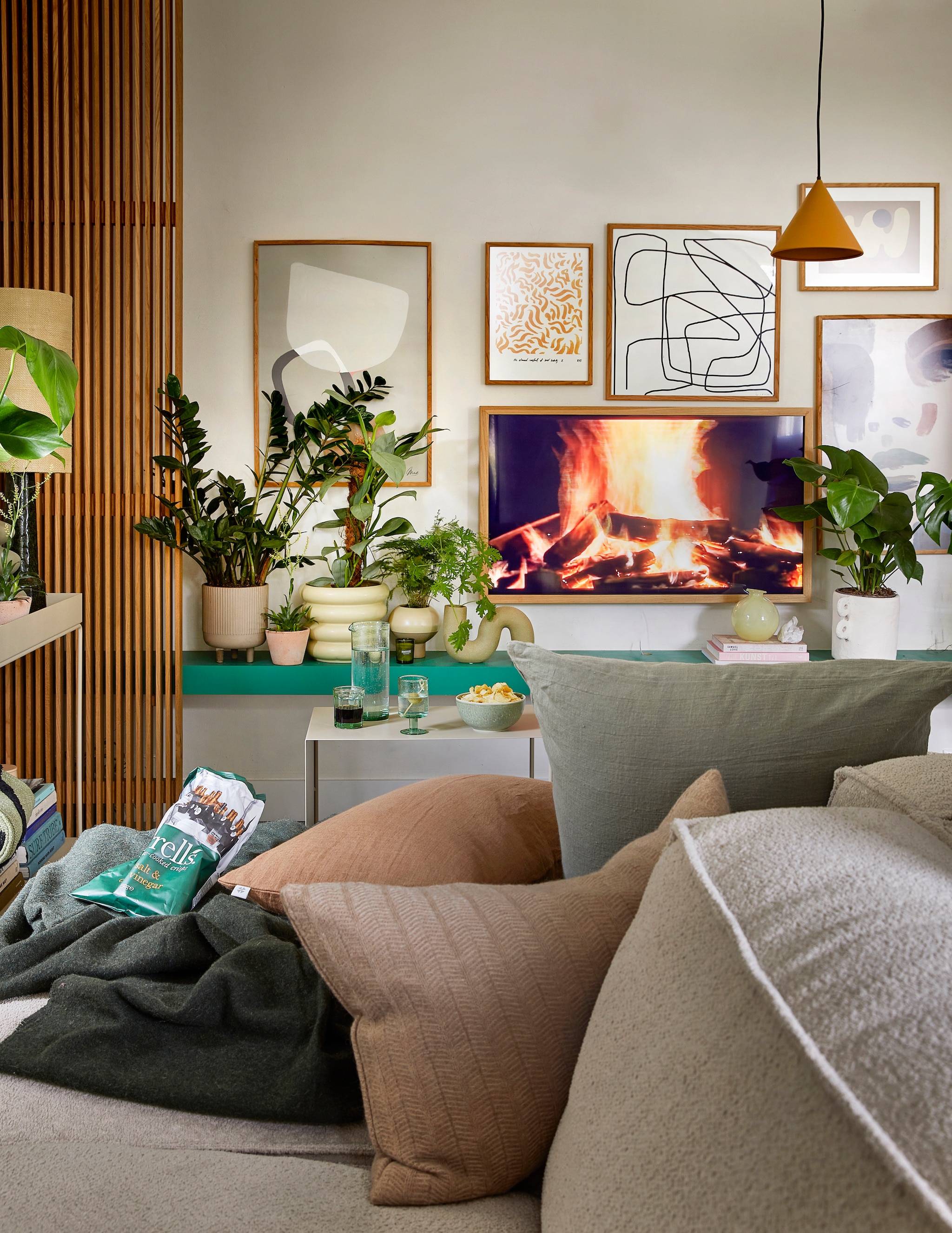 Linnen kussen Olive, 60×60 cm € 69,-, linnen kussen Cinnamon, 40×60 cm € 59,- (bymolle.com). Lichtbruin kussen met visgraatmotief Kata van Oyoy, 40×60 cm € 57,80 (wonenmetlef.nl). Donkergroene merinowollen deken van McNutt, 200×145 cm € 100,-, groen glas van Serax, medium € 9,50, groen aardewerken schaaltje Miscellaneous € 7,- (vanmanenaantafel.nl). Grijze terracotta plantenpot op poten van Kristina Dam, 18x18x22 cm € 89,-, op de muur v.l.n.r.: poster 03 van Studio Mae van Paper Collective, 50×70 cm € 55,-, poster Comfort Yellow, 30×40 cm € 35,-, poster Her van Paper Collective, 50×70 cm € 55,-, eikenhouten lijst van Paper Collective, 30×40 cm € 35,-, eikenhouten lijst van Paper Collective, 50×70 cm € 55,-, gerecycled wijnglas Oli van Ferm Living € 25,-, gerecyclede glazen karaf Oli Jug van Ferm Living € 39,-(byjensen.nl). Terracotta bloempot Rosa, 12 cm (Ø) € 9,50 (bymolle.com). Beige geribbelde pot Awa Large in Butter van Oyoy, 25,7×22 cm (Øxh) € 70,55, gele vaas Hagi van Oyoy, 15×15 cm € 34,- (wonenmetlef.nl). Vaas Object in Matt Olive van HKliving € 34,99, witte papier-maché pot met oren van Serax € 55,-, oranje ijzeren hanglamp Triangle van HKliving, 25×22 cm € 95,- (vtwonen.nl). Ecru glazen vaas € 24,95, planten vanaf € 4,95 (stadstuindebloemenpoort.nl). Bergkristal € 75,- (eduard-leiden.nl). Televisie The Frame met eikenhouten lijst, vanaf € 1099,- (samsung.com). Ecru elementenbank Square van Easy Sofa, per module vanaf € 605,- (hoekbankxxl.nl). Lijntekening en boeken privébezit. vtwonen 02-2023 | styling Femke Pastijn | fotografie Peggy Janssen