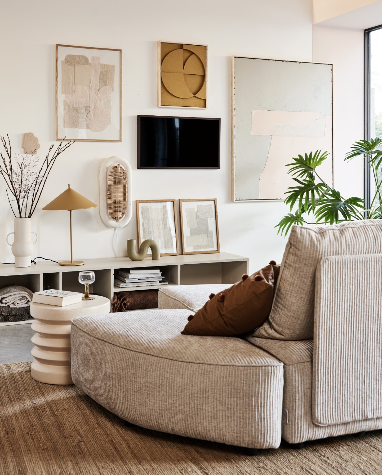 Televisie The Frame 32 inch € 429,-, verwisselbare walnoothouten lijst The Frame € 129,- (samsung.nl). Kast in kleur Skimming Stone 241 van Farrow &amp; Ball AFMETING € XXX,- (combitex.nl). Handgemaakte ovalen wandlamp NAAM € 299,- (lanena-home.com). Sofa Hunter bestaat uit diverse losse onderdelen: poef € 419,-, element met rug € 1009,-, element zonder rug € 419,- (zuiver.nl). Bruin sierkussen met pompons van MERK € 29,95, roze bijzettafel van MERK € 159,-, vaas van MERK AFMETING € 47,95 (vtwonen.nl). Hennep vloerkleed 180×280 (bxl) € 395,-, olijf/nude-kleurig abstract kunstwerk (rechts) 100×120 cm (bxh) € 549,-, okergeel kunstwerk boven tv van 43x4x53cm (bxdxh) € 329,-, taupekleurig wandornament Face € 37,95, crèmekleurige bijzettafel 38×36 cm (Øxh), wijnglazen met groene voet € 9,95, okergele lamp Triangel € 149,- (hkliving.nl). Stoffen kunstwerk in eikenhouten lijst € 89,-, kunstwerken in lijst op kast, per stuk € 69,- (sur-atelier.nl). Bruine en beige katoenen plaids in dressoir 130×170 cm per stuk € 45,99 (zarahome.com). Donkerbruin plaid rechts in dressoir 130×170 cm (bxl) € 65,- (maisonnl.com). Overig privébezit. vtwonen 02-2022 |  Styling Esther Jostmeijer | Fotografie Bart Brussee