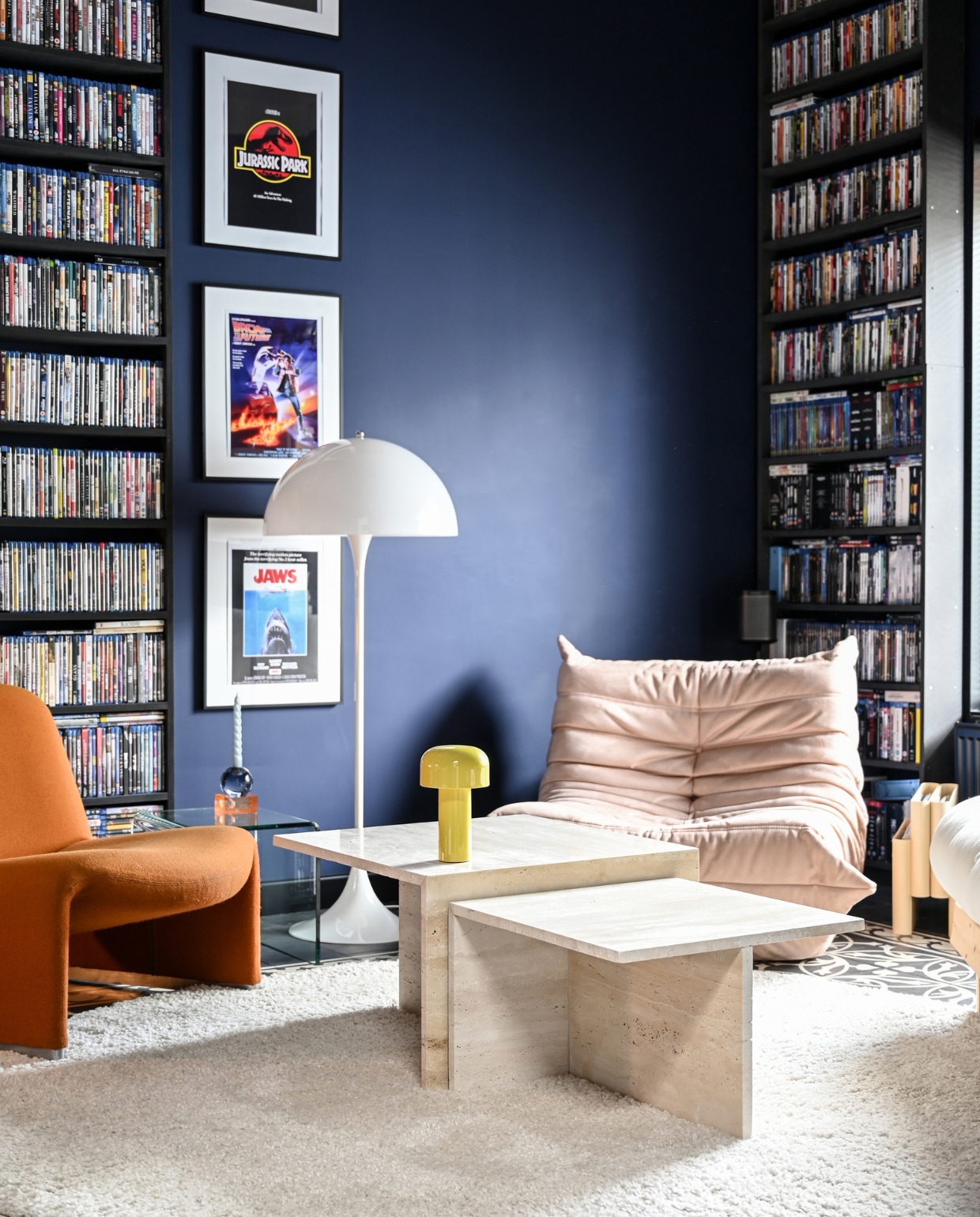 Matte muurverf U2.21.09 Sikkens. Vloerkleed RugVista. Oranje vintagestoel Alky van Artifort. Beige stoel Togo van Ligne Roset. Glazen bijzettafel ted. Amsterdam. Zelf gestapelde, glazen kandelaars Fést Amsterdam. Vloerlamp Panthella van Louis Poulsen. Salontafels Stoned. Draagbare lamp Bellhop van Flos. Vintage lectuurbak Kartell. vtwonen 01-2023 | styling & fotografie Ellis & Michiel