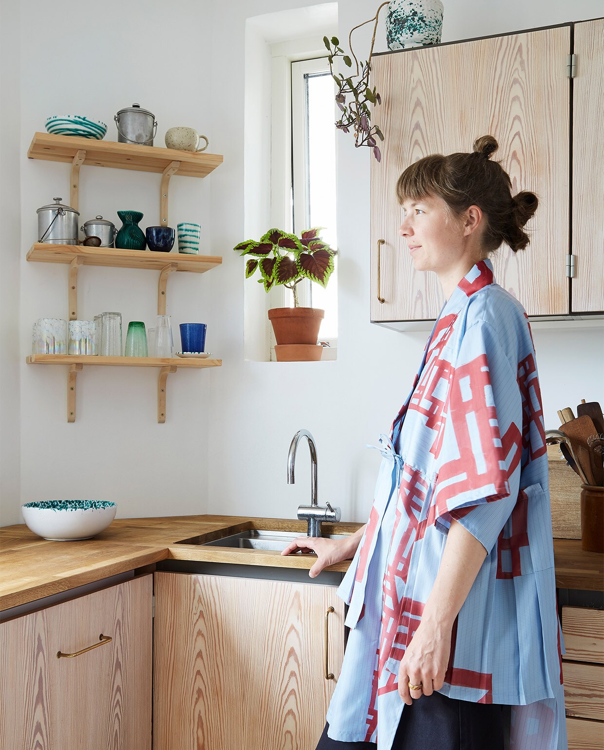 Keuken via dba.dk, de Deense Marktplaats. Servies en glazen van reizen en rommelmarkten. Kimono van Siffs eigen label Anew (siff.bigcartel.com). Over de keuken zegt ze dit: ‘In plaats van een nieuwe keuken te kopen, hebben we die online tweedehands opgespeurd, de deuren geschuurd en met whitewash behandeld en een houten blad op maat toegevoegd.’ vtwonen binnenkijken special 2022 | styling Rikke Graff Juel | fotografie Annita Behrendt