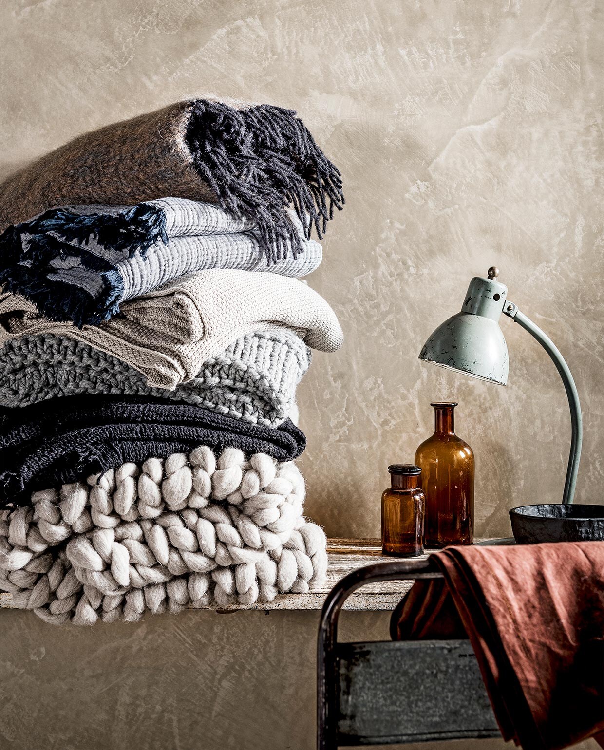 Van boven naar onder: mohair plaid van de Wolwaeren Shore Line collection in kleur Seaweed € 229,- (Studio Ro Smit). Vergrijsd blauwe gekreukte deken met franje, 150×210 € 99,- (Hay Amsterdam). Ecrukleurige gehaakte plaid € 69,95 (Dille &amp; Kamille). Grijze gehaakte plaid € 59,99 (H&amp;M Home). Zwarte wafeldeken Svärtan € 34,95 (Ikea). Grof gehaakte wollen deken,100×150 cm € 220,- (Vacht van Vilt). Metalen stoel € 59,-, sidetable € 229,95 (Raw Materials). Apothekerspotten vanaf € 9,95 (De Weldaad). Bureaulamp € 325,- (Neef Louis). Zwarte kom Svärtan € 5,99 (Ikea). vtwonen 02-2017 | styling Danielle Verheul | fotografie Sjoerd Eickmans