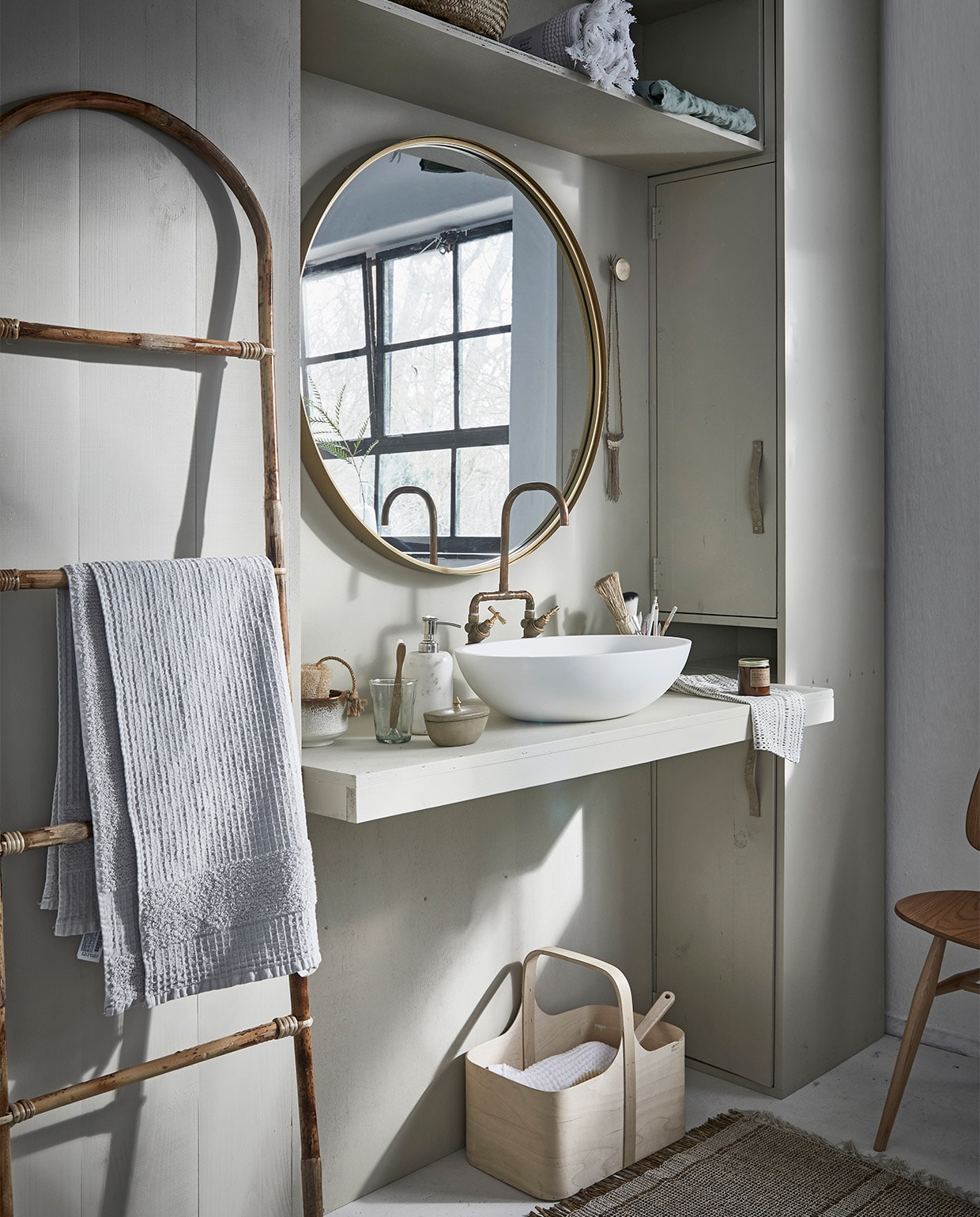 Grote ronde spiegel, marmeren zeeppomp (Nordal). Bamboe ladder, vloerkleed (Madam Stoltz). Witte wafeldoek (De Weldaad). Stoel Butterfly van Ercol (De Machinekamer). Berkenplex opbergmand (Nordic New). Grijze handdoek (Zara Home). Waskom Girona (Ton Scholten). Kraan (Jan van IJken Oude Bouwmaterialen). Tadelakt zandkleurig potje met deksel (MaisonNL). Bureaulamp (Vint. Amersfoort). Glas, linnen doek in opbergzak, witte opgerolde wafeldoek (De Weldaad). Zandkleurig met bruine kom, messing muurknop van Ferm Living, geurkaars in bruin glazen potje (Six and Sons). Rieten mand in kast vanaf (H&amp;M Home). Badborstel (Dille &amp; Kamille). De kast is geschilderd in de kleur Bone van Farrow &amp; Ball (De Ru). De muur is geschilderd in de kleuren Egg White en Light Grey van vtwonen (Karwei). vtwonen 05-2018 | styling Cleo Scheulderman | fotografie Jeroen van der Spek