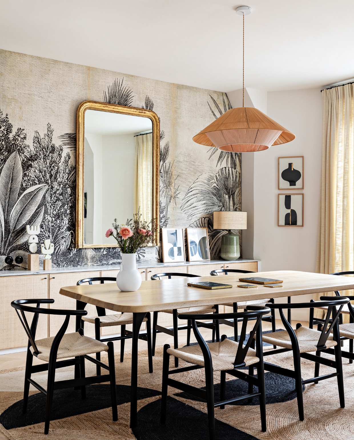 Eiken tafel Oasis van Maison Sarah Lavoine. Stoelen Carl Hansen & Søn. Hanglamp Maison Paloma. Spiegel vintage. Behang Le Monde Sauvage. Witte vaas HKliving. Lamp met groene voet Zara Home. Schilderijen Floating House Collection. Vloerkleed Elitis. Overig onbekend. vtwonen 12-2022 | styling Marie-Maud Levron | fotografie Yann Deret