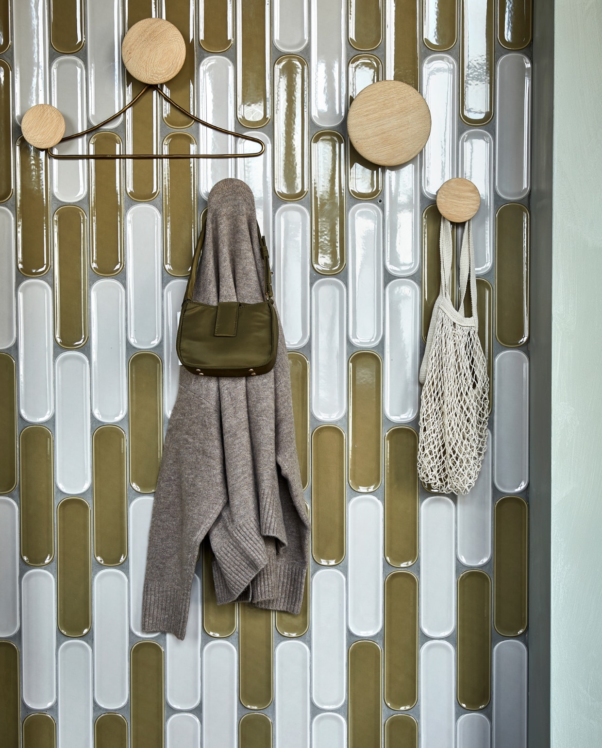 Wandtegels Shapes Greige Round glans, 7,5x30 cm per m² € 68,99,  wandtegels Shapes Olive Round glans, 7,5x30 cm per m² € 68,99. M.m.v. vtwonen.nl (wandhaken van Muuto), zarahome.com (messing kledinghanger), zara.com (tas, hoed). Overig privébezit. vtwonen 02 2023 | productie Tanja Saarberg | styling Sanne Ketelaar | fotografie Peggy Janssen