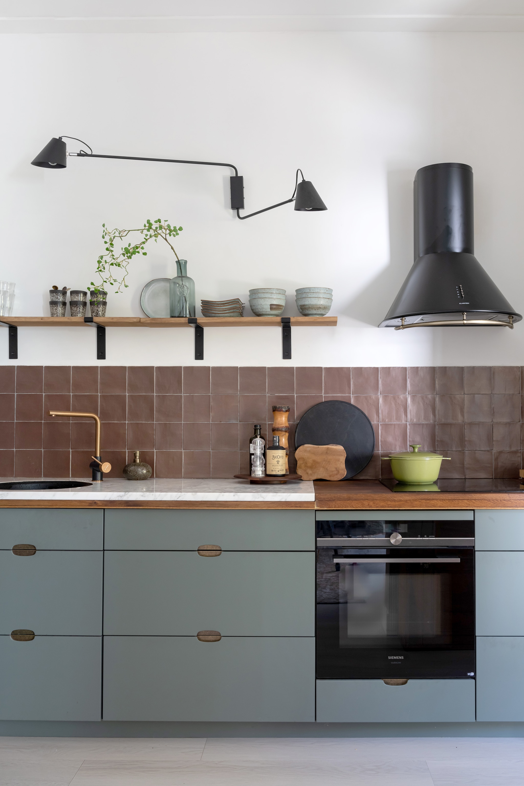 (Binnenkijker) Keuken Kvik, aanrechtblad en wandplanken zelfgemaakt, tegels Tegeldump, kraan Pyramis, zeepdispenser Bijenkorf, wandlamp Qazqa, koelkast Smeg, mokken HKliving, fles en bord Intratuin, borden en kommen Tokyo Design, afzuigkap Klarstein, pan Le Creuset, snijplanken Dille &amp; Kamille, zwart dienblad H&amp;m, houten decoratie kringloop. styling Sharon Roest | fotografie Caroline Martinot