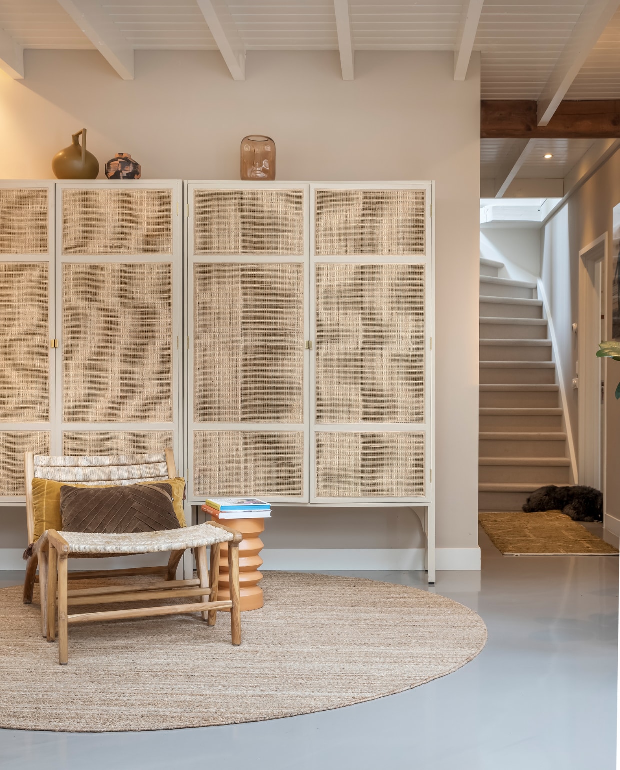 Muurverf Mushroom van Little Greene, verf plafond RAL 9010, vloer gietvloer. Kasten HKliving. Vazen op kasten van links naar rechts: HKliving en laatste H&M. Stoel HKliving, kussens op stoel HKliving en Loods 5. Bijzettafel, rond vloerkleed en kleed voor trap HKliving. Overig onbekend. vtwonen 02-2023 | styling Karin van Schie | fotografie Henny van Belkom