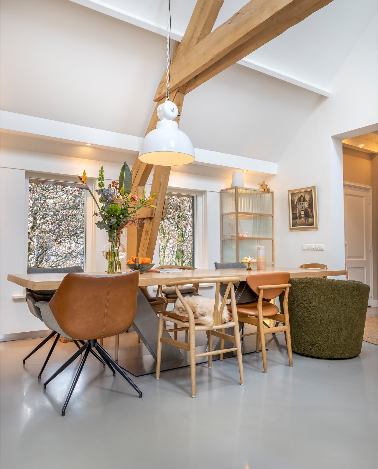 Muurverf en verf plafond RAL 9010, vloer gietvloer. Kuipstoelen leer Zuiver, overige stoelen MisterDesign. Kandelaar Sissy-Boy. Taartplateau H&M. Kan, hanglamp en vitrinekast HKliving. Schilderij antiekmarkt. Overig onbekend. vtwonen 02-2023 | styling Karin van Schie | fotografie Henny van Belkom