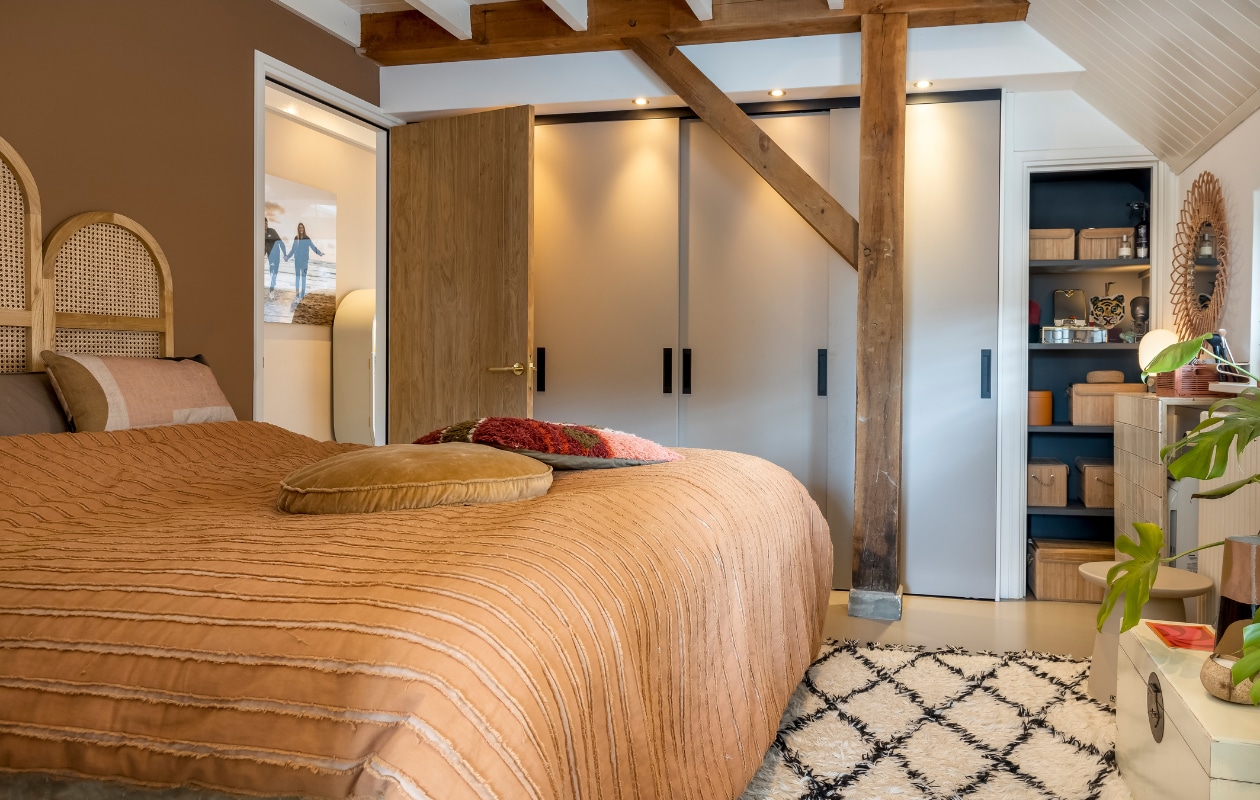 Muurverf Book Room Red van Farrow & Ball, verf plafond RAL 9010. Bed Slaaphof. Hoofdbord, sprei en kussens op bed HKliving. Kastenwand op maat gemaakt. Verf in kast Zwart Mat van Painting The Past. Opbergmanden in kast Xenos, spiegel in kast Sissy-Boy, tijgerkop Doing Goods, lampje Ikea. Rotan spiegel Kwantum. Betegelde kast zelfgemaakt door buurman. Roze mandje Hema. Vloerkleed HKliving. Overig onbekend. vtwonen 02-2023 | styling Karin van Schie | fotografie Henny van Belkom