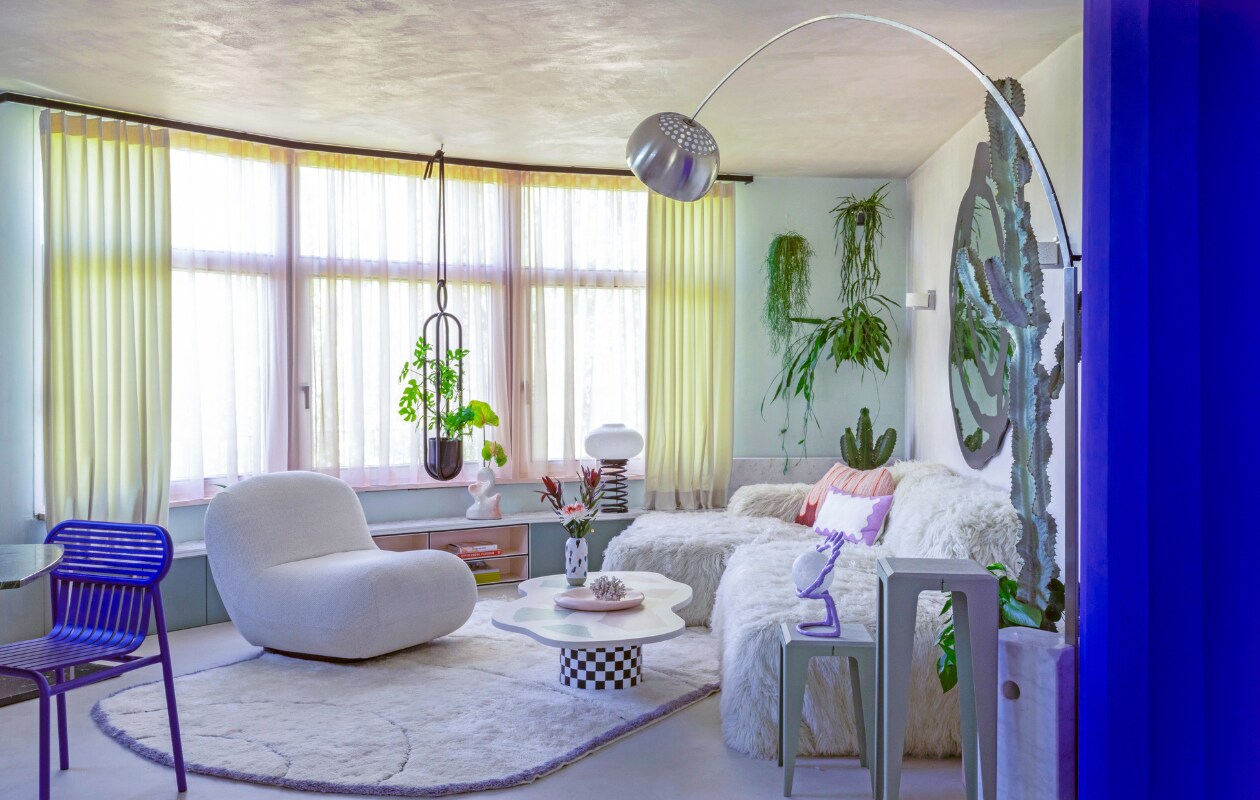 Gordijnen Ado Goldkante. Lage wandkast op maat gemaakt. Organische vaas Hannah Simpson Studio. Spiraallamp vintage. Plantenhanger Atelier Haussmann. Blauwe stoel Petite Friture. Fauteuil Chelsea BoConcept. Vloerkleed eigen ontwerp, handgemaakt in Marokko. Op maat gemaakte salontafel Minerva Artlab. Vaas Studio Arhoj. Roze bord Moustache. Bank Pyllow Mycs, schapenwollen bekleding zelfgemaakt. Bijzettafels Chamfer Wye Design. Paarse oog-lamp mattina moderna. Vloerlamp Arco Flos. productie, fotografie &amp; tekst Anne Catherine Scoffoni | tekstbewerking Caroline Westdijk