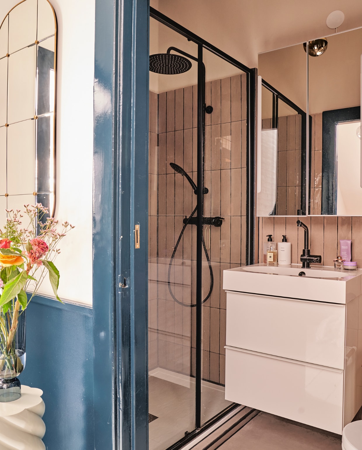 Witte pilaar &amp;klevering, vaas Hay, spiegel Zara Home, badkamermeubel en spiegelkast Ikea, douchekop en -kraan Tiger, wandtegels in Latte glans van Tegels in huis, verf deurkozijn Hague Blue van Farrow &amp; Ball. vtwonen 02-2023 | productie CocoFeatures.com | fotografie Muk van Lil