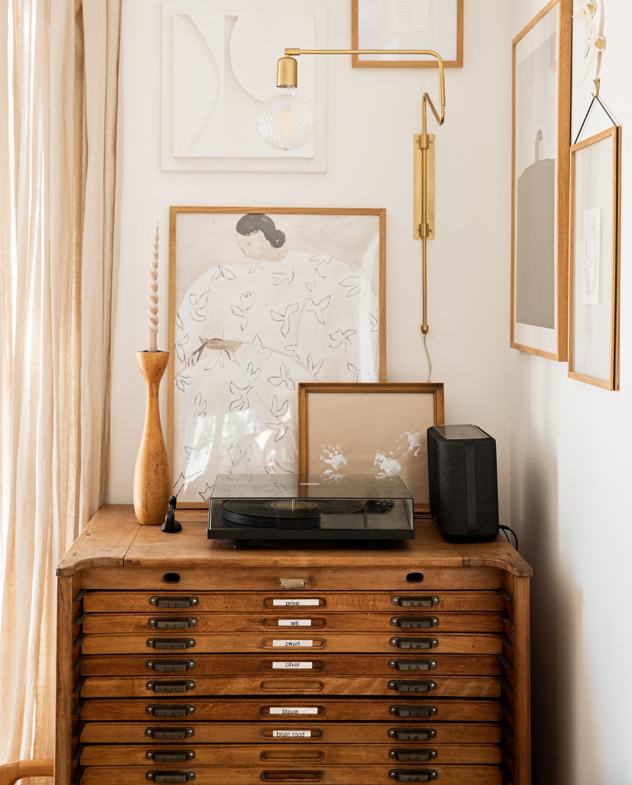 Ladekast Marktplaats, posters PSTR Studio, 3D-kunstwerk en handjes van Koosje zelfgemaakt, klein houten kunstwerk Ruben van der Scheer, kandelaar van kringloopwinkel, wandlamp House Doctor, platenspeler Pro-Ject, speaker Denon. vtwonen 09-2022 | styling Ilona Jongepier | fotografie Diana van leeuwen