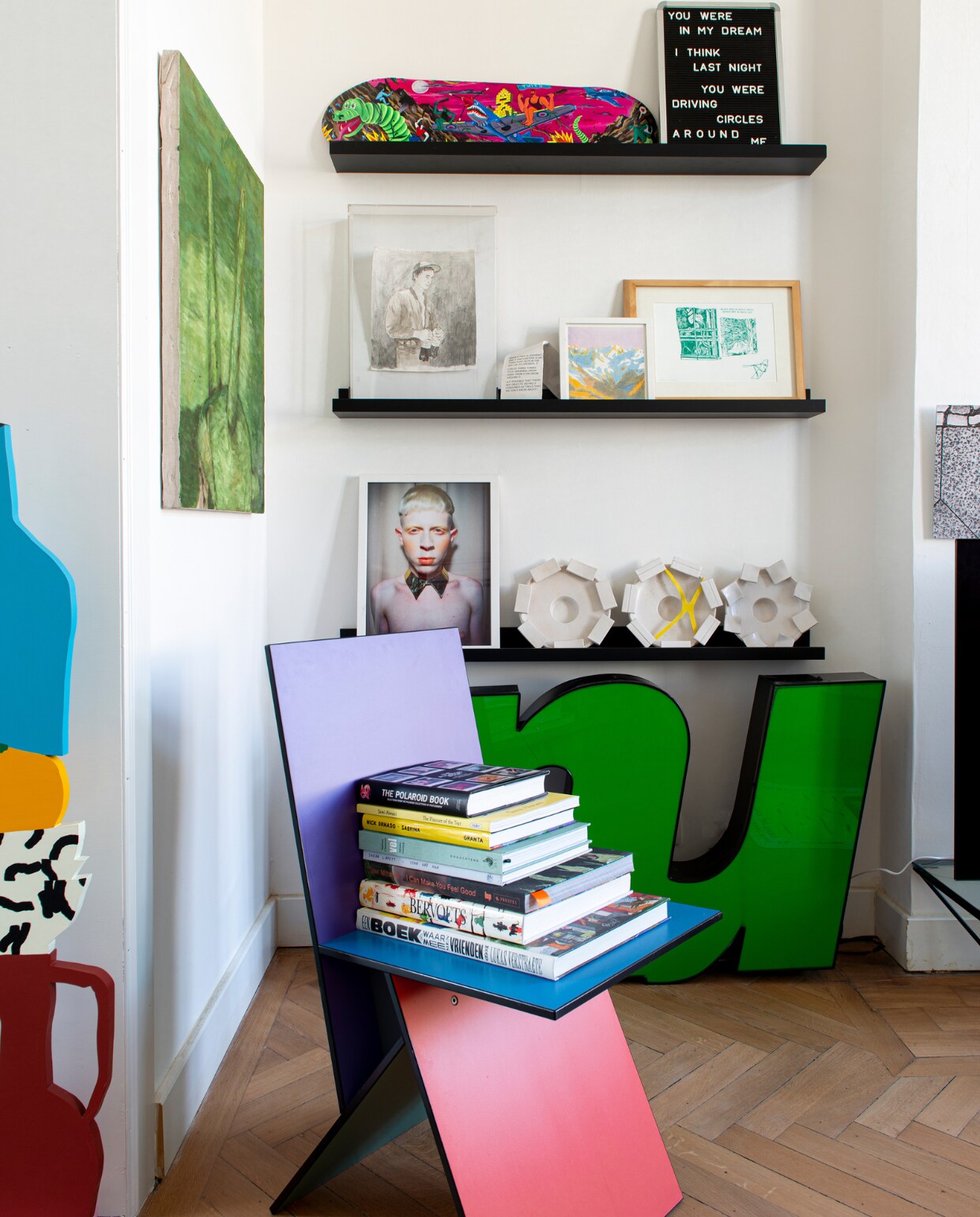 Stoel van Verner Panton voor Ikea, links sculptuur We Are Out of Office, groen schilderij Josse Keppens, skateboard Brecht Vandenbroucke, eronder tekening Ward Zwart, daarnaast tekening Joost Stokhof, eronder aardewerk Carla van Ouwenaller, daarnaast foto Ignacio Trias. Planken Ikea, letters Instagram, overig onbekend. vtwonen 02-2023 | productie De Binnenkijkers | styling Jeske Weel | fotografie Caroline Coehorst