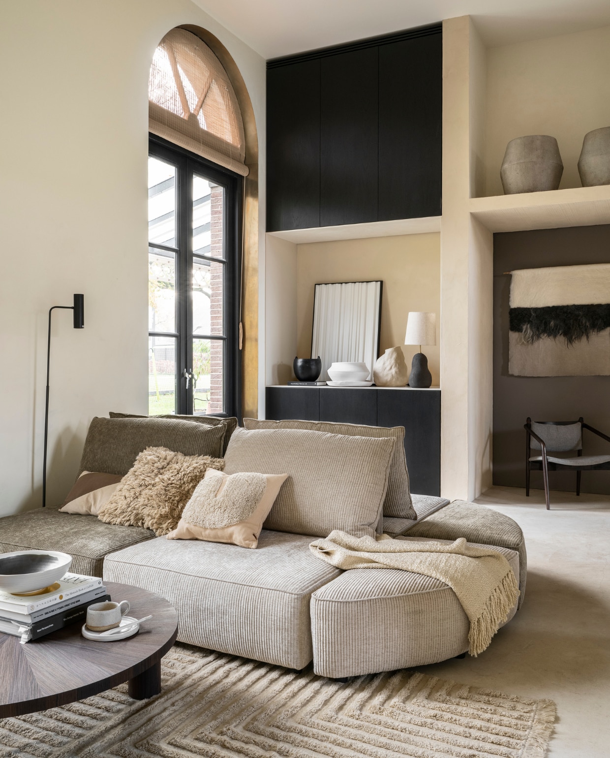 Stucco-look muurverf Mykonos, 2,5 liter € 110,- (wearewowmakers.com). Duurzame bruine muurverf in kast Harbour no. 968 van Lab Paint, 1 liter € 48,- (vestingh.nl). Ribfluwelen elementenbank Hunter, per element vanaf € 380,- (zuiver.com). Salontafel van Ferm Living € 1289,-, grote potten van Serax € 469,-, schaal op salontafel van Ferm Living € 62,- (flinders.nl). Vloerkleed van Ferm Living, vanaf € 395,-, hoogpolig kussen van Ferm Living € 135,-, kussen met organische vorm van Ferm Living € 79,-, kussen met diagonale streep Riley van Moos € 24,95, plaid van Malagoon € 59,99, zwarte vloerlamp van Bloomingville € 179,-, stoel van Dutchbone € 299,-(vtwonen.nl). Handgemaakt wandkleed van Babette Leertouwer, duurzame Nederlandse schapenwol en Belgisch linnen, 175x103 cm € 350,- (halona.nl). Pot met oren € 62,95, witte schaal € 59,95, witte pot € 59,95 (urbannature- culture.com). Vaas organische vorm € 119,- (loods5.nl). Tafellamp van Ferm Living € 348,- (lampenmaster.nl). 3D-kunstwerk € 425,- (studiolde.nl). Mok, schotel en lepel vanaf € 20,-(studio-potterdam.com). vtwonen 03-2023 | styling Marianne Luning | fotografie Stan Koolen | assistentie Pom Rezelman, Evans van der Sluis | naaiwerk Meta Poulain