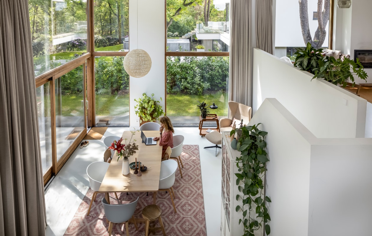 Martine in haar duurzaam gebouwde houtskeletvilla. Gordijnen Curtaincy, lamp Zuiver, tafel en fauteuil Bolia, eetkamerstoelen Hay. Vintage schoolstoelen, apothekerskast en kleed van Desso via Marktplaats. Kruk Nijhof, vintage trolley Huisjeboompjevintage, tafellamp Sissy-Boy. vtwonen 03-2023 | styling Martine Jeuken | fotografie Henny van Belkom