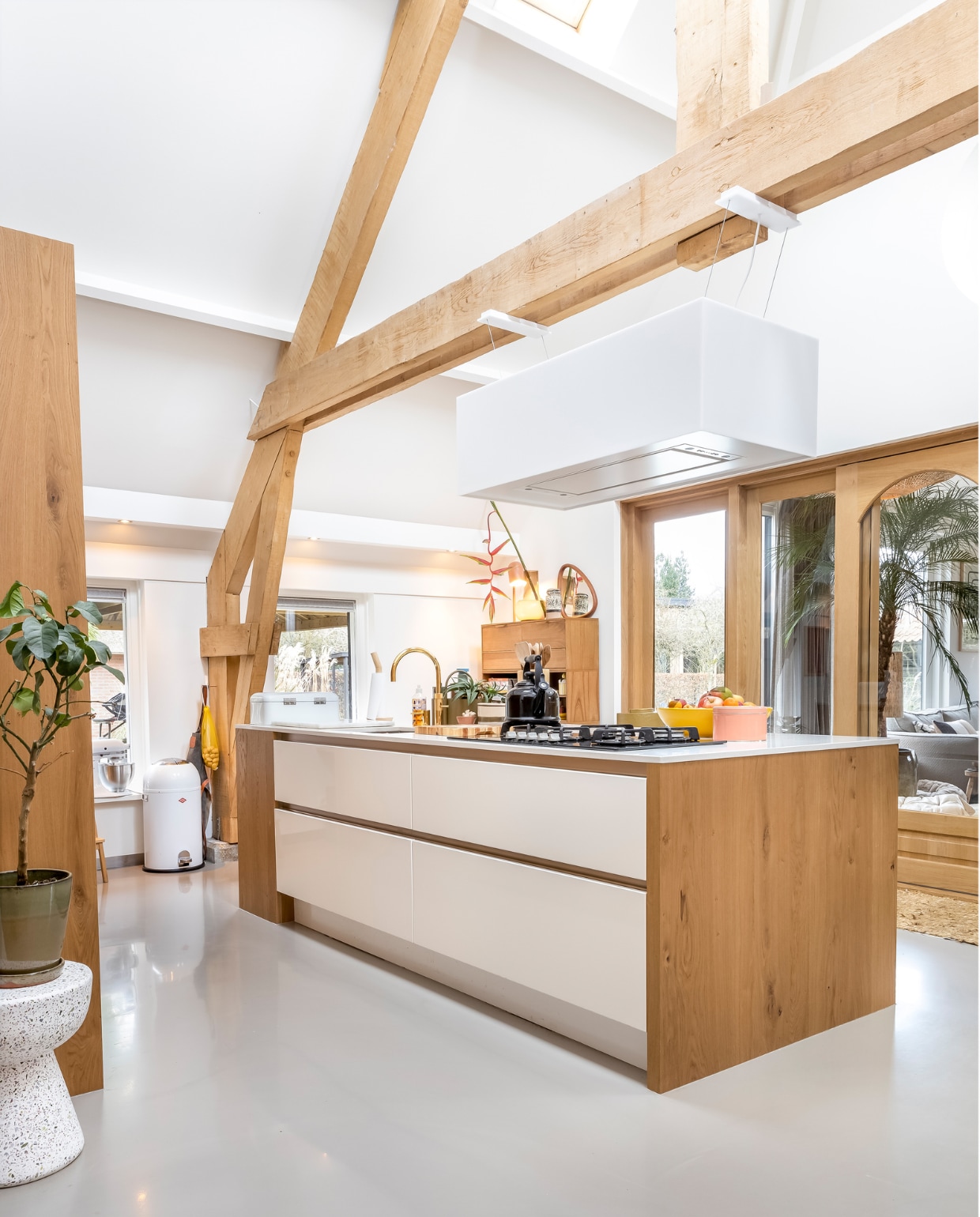 Muurverf en verf plafond Ral 9010, vloer gietvloer. Kruk links, kast en roze doosje HKliving. Keuken Smit Keukens. Pedaalemmer Wesco. Schort Witloft. Kraan Quooker. Fluitketel Le Creuset. Fruitschaal Des Pots. Afzuigkap Novy. Op de kast: lamp It’s About Romi, spiegel Zara Home, vaas MD Living, bloem Little Shop of Flowers. Overig onbekend. styling Karin van Schie | fotografie Henny van Belkom