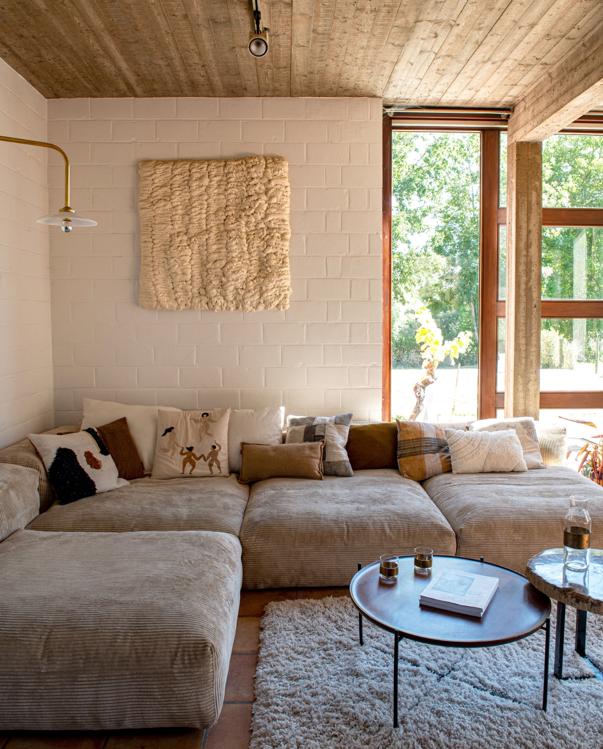 Lamp Muller van Severen van Valerie Objects via La Fabrika. Bank Vetsak. Kunstwerk zelfgemaakt met isolatieschuim. Salontafels Swapp.Tapijt Ikea. Kussens Ferm Living en Zara Home. Lamp aan het plafond zat al in het huis. Glaswerk op tafel Serax. vtwonen 03-2023 | productie De Binnenkijkers | styling Jeske Weel | fotografie Caroline Coehorst