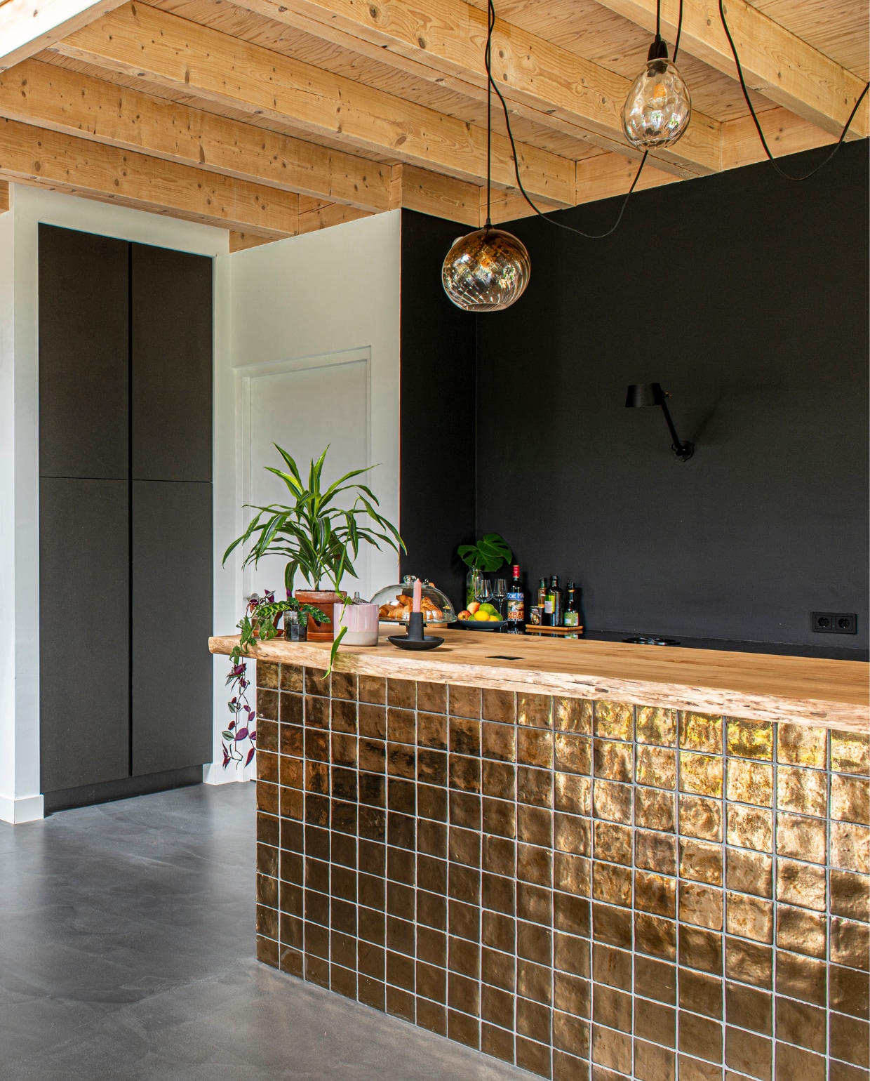 Gouden tegels bar Cottoceramix via Patroonfabriek, keuken en acaciahouten barblad Meubelmakerij Mark, hanglampen Made, zwarte muurlamp Tonone. vtwonen 03-2023 | productie De Binnenkijkers | styling Jeske Weel | fotografie Caroline Coehorst