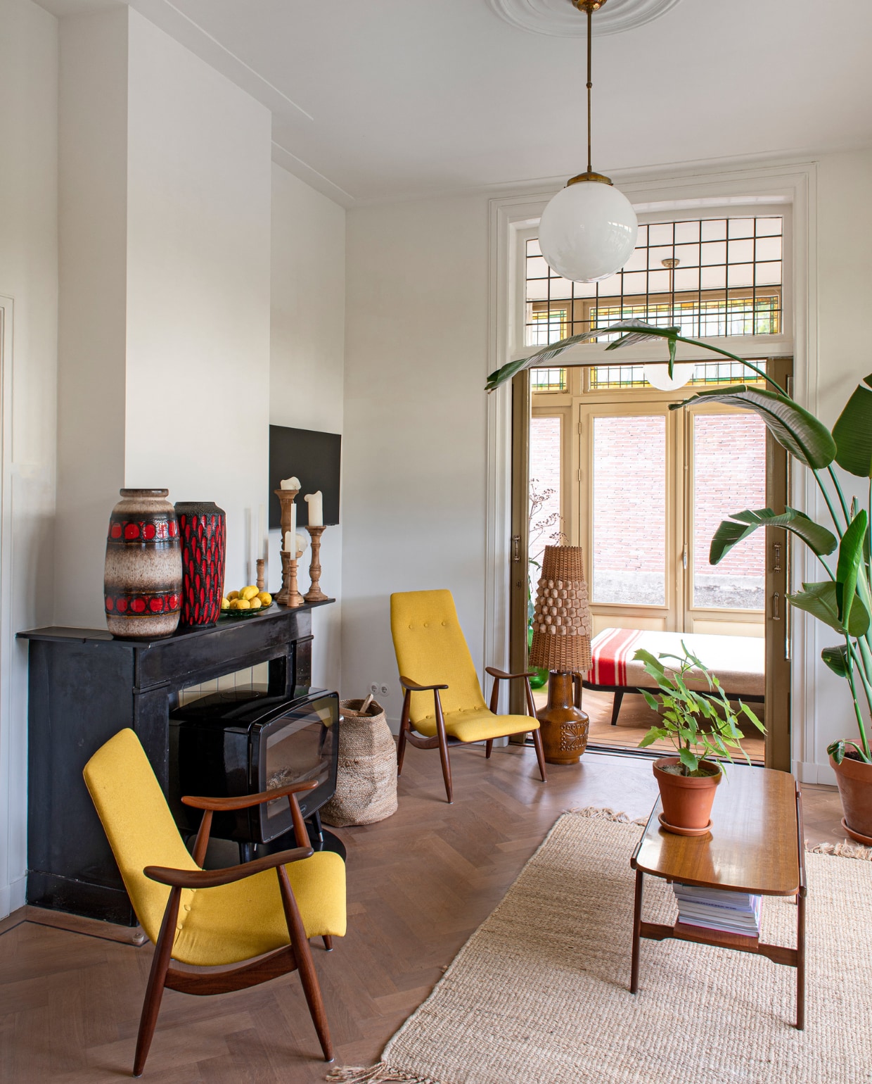 De haard en schouw zaten al in het huis. Ook de serredeuren zijn nog origineel. Vazen uit Berlijn. Kandelaars Zutphense Hand. Louis van Teeffelen-fauteuils en vloerlamp Vanouds Schalkhaar. Mand Sissy-Boy. Hanglamp Marktplaats. Vloerkleed Stilleven. Bed in serre Cleopatra van Auping. Deken Marktplaats. Overig onbekend. vtwonen 03-2023 | styling &amp; fotografie Caroline Coehorst i.s.m. Studio Daan Hietbrink