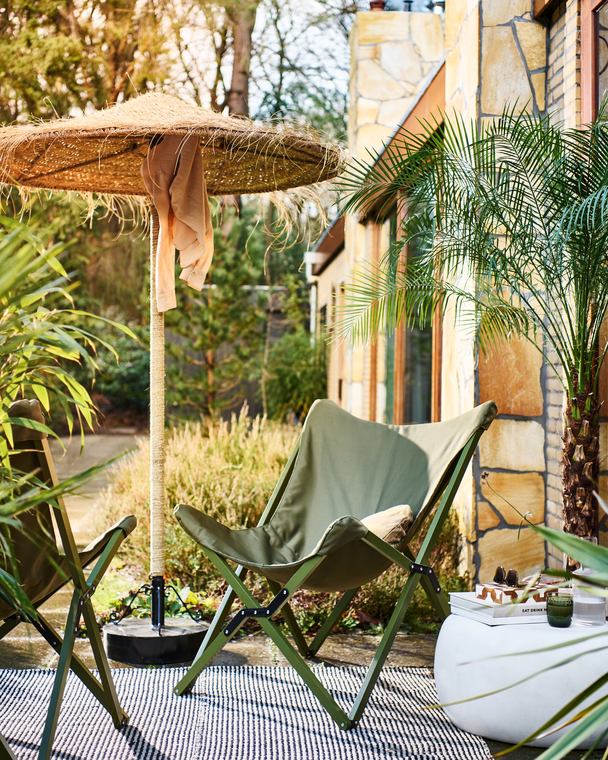 Opvouwbare buitenstoelen Lazy Afternoon in camouflage groen, 85x77x92 cm (bxdxh) € 169,-. Bijzettafel Pebble in betonlook wit, 65x49x31 cm (bxdxh) € 199,-. Ook verkrijgbaar in 50x35 cm (Øxh) € 179,- en in antraciet. M.m.v. householdhardware.nl (parasol, parasolvoet), vtwonen.nl (kussen, waterglas). Overig privébezit. vtwonen 04-2023 | productie Tanja Saarberg | styling Marlies Does | fotografie Sjoerd Eickmans