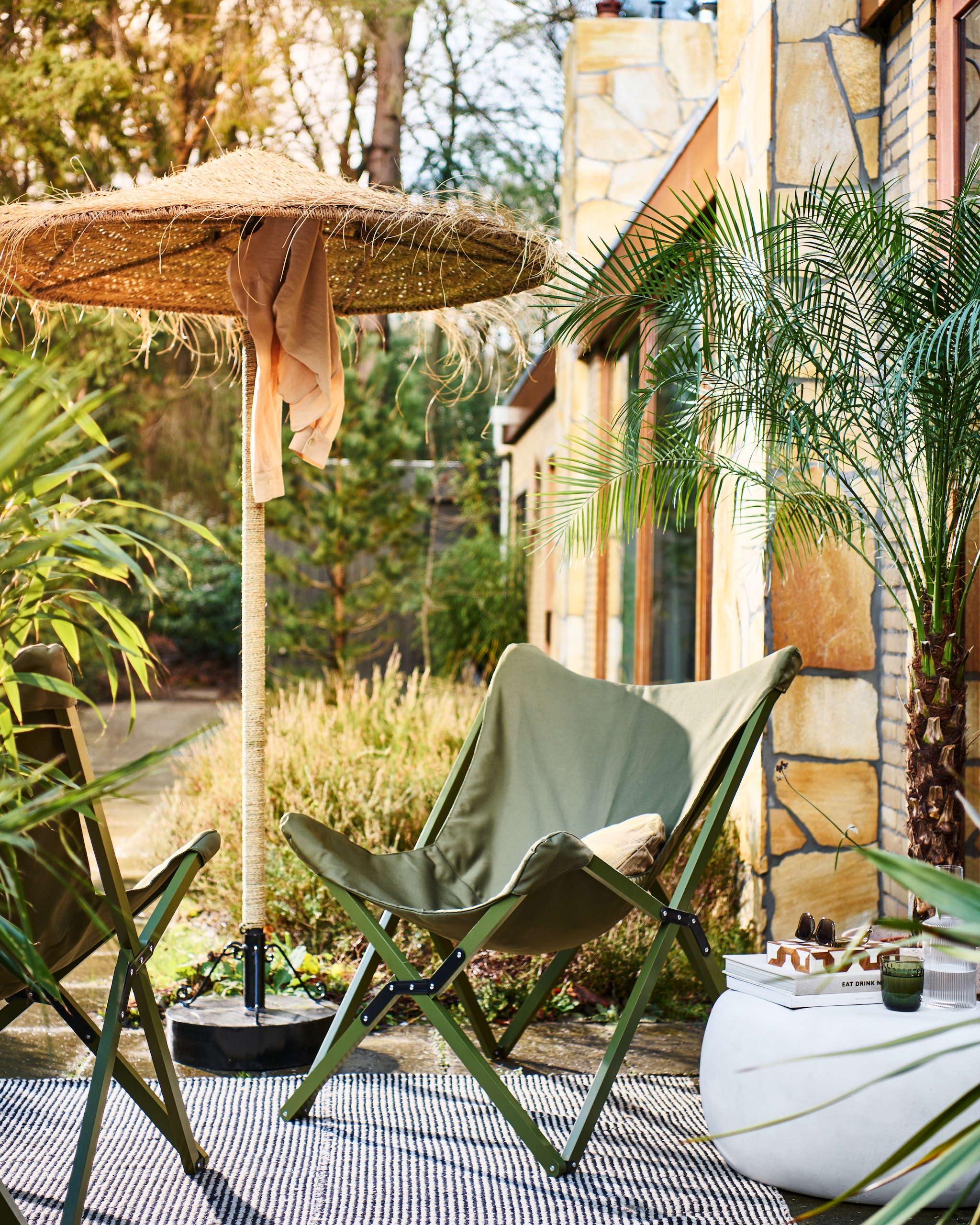 Opvouwbare buitenstoelen Lazy Afternoon in camouflage groen, 85x77x92 cm (bxdxh) € 169,-. Bijzettafel Pebble in betonlook wit, 65x49x31 cm (bxdxh) € 199,-. Ook verkrijgbaar in 50x35 cm (Øxh) € 179,- en in antraciet. M.m.v. householdhardware.nl (parasol, parasolvoet), vtwonen.be (kussen, waterglas). Overig privébezit. vtwonen 04-2023 | productie Tanja Saarberg | styling Marlies Does | fotografie Sjoerd Eickmans