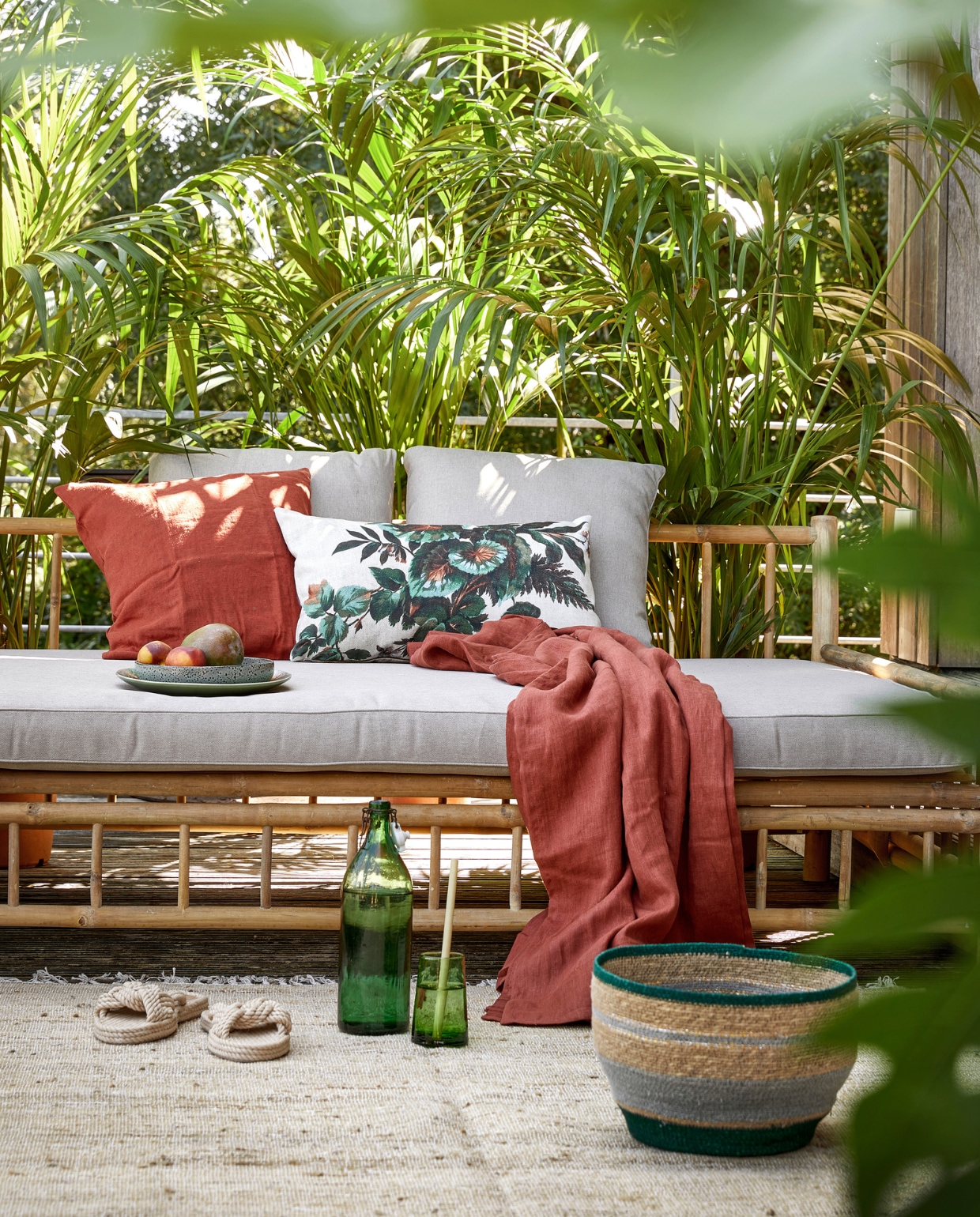 Bamboe daybed van Exotan. Steenrood linnen kussen Vigdis, steenrode linnen doek Dytag Ikea. Gebloemd kussen Kyoto HK Living. Oude fles Van Dijk &amp; Ko. Glas Household Hardware. Grijs-groene mand Nile, per set van twee, vloerkleed Wabi Sabi Zenza Home. Instappers H&amp;M. Overig privébezit. vtwonen special tuin 06 | styling Moniek Visser | fotografie Peggy Janssen | assistentie Mirjam Gesink, Sanne Kiesling