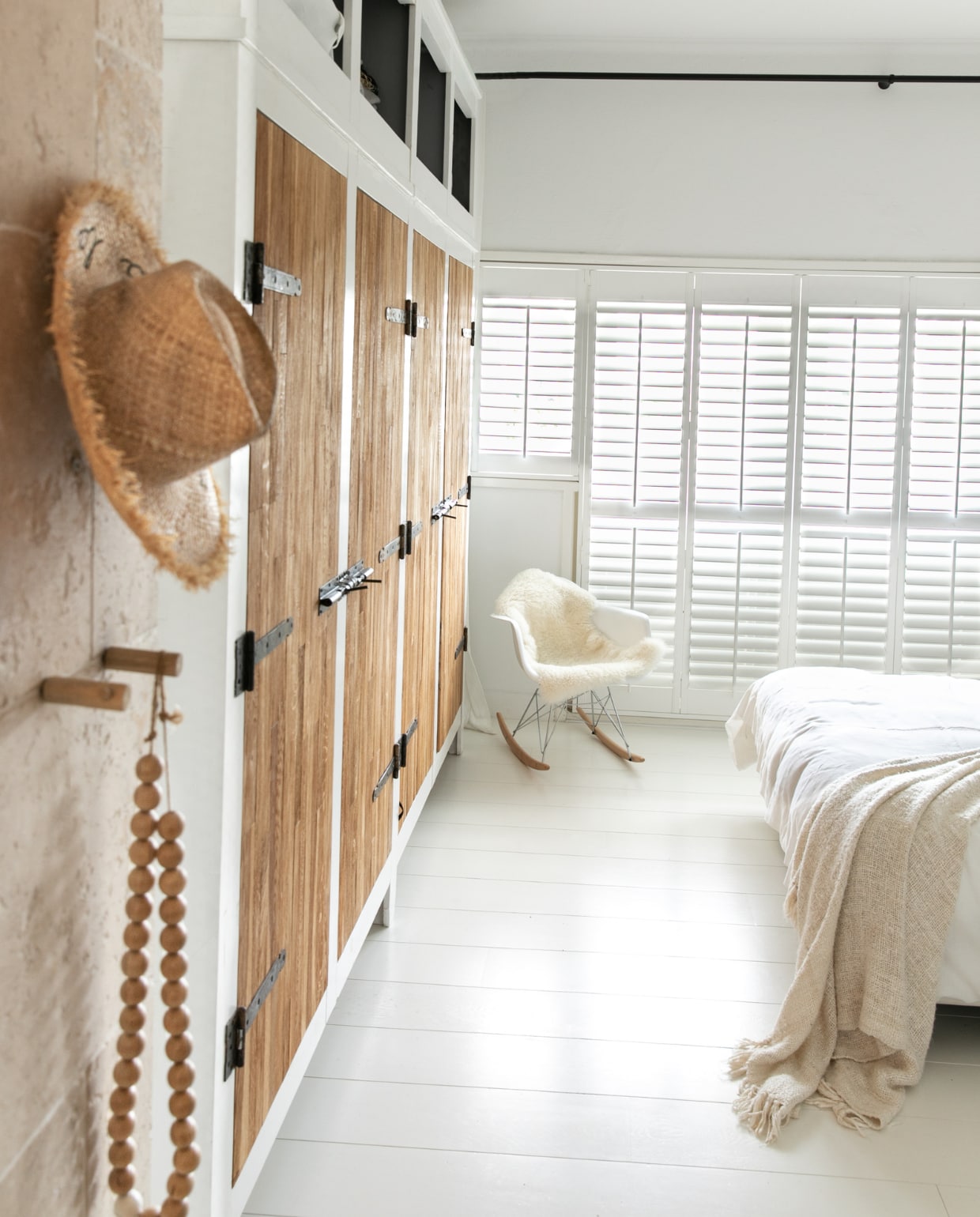 Slaapkamerkasten eigen ontwerp, travertin tegels, schommelstoel Eames, sprei Bazar Bizar, wandkleur Ral 9010, wit gelakte eikenhouten vloer. vtwonen 04-2023 | fotografie Monique Koelman