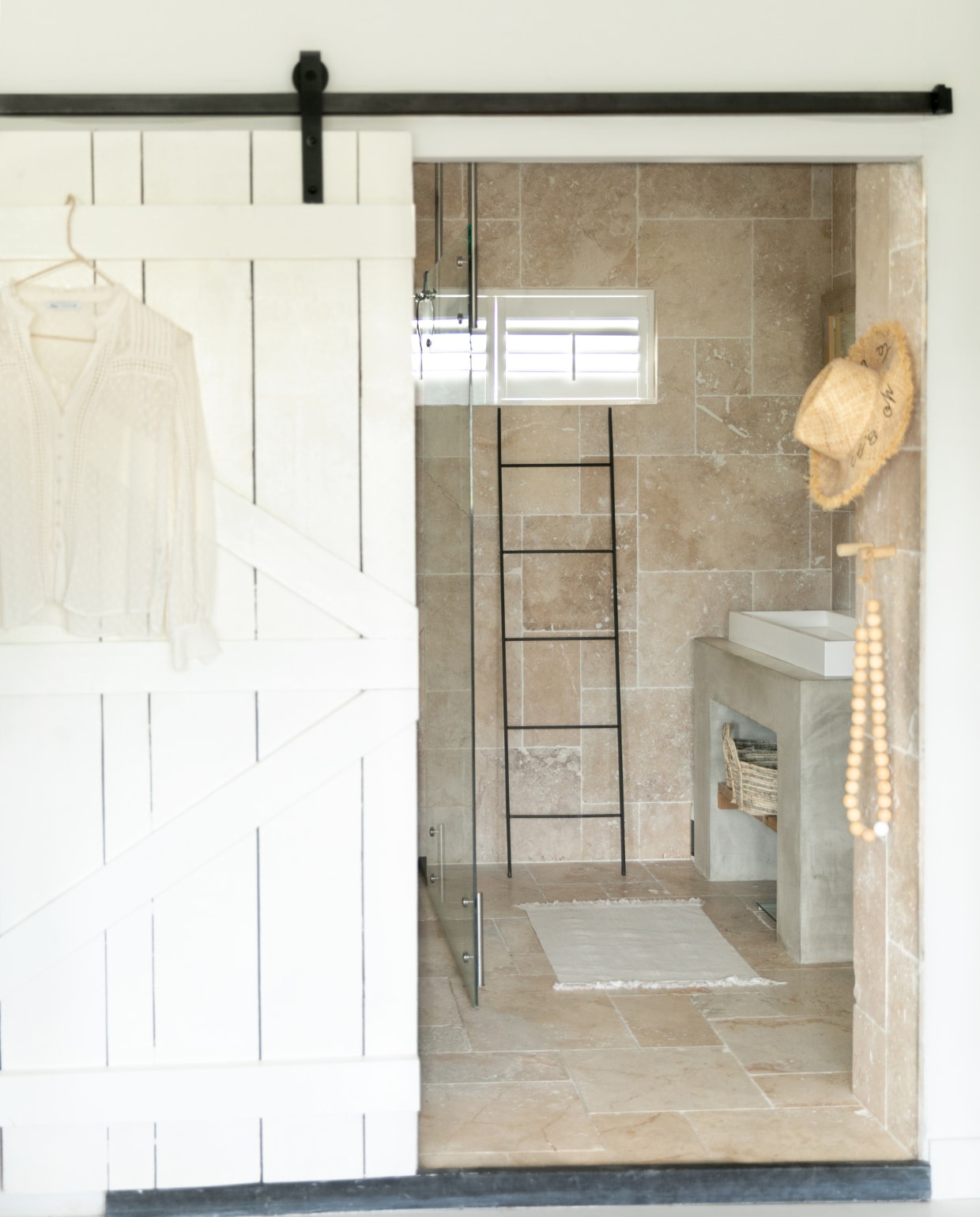 Badkamer eigen ontwerp, tegels gemaakt van travertin, wasbak Duravit, boerderijdeur eigen ontwerp, hoed uit Marrakech. Overig onbekend. vtwonen 04-2023 | fotografie Monique Koelman