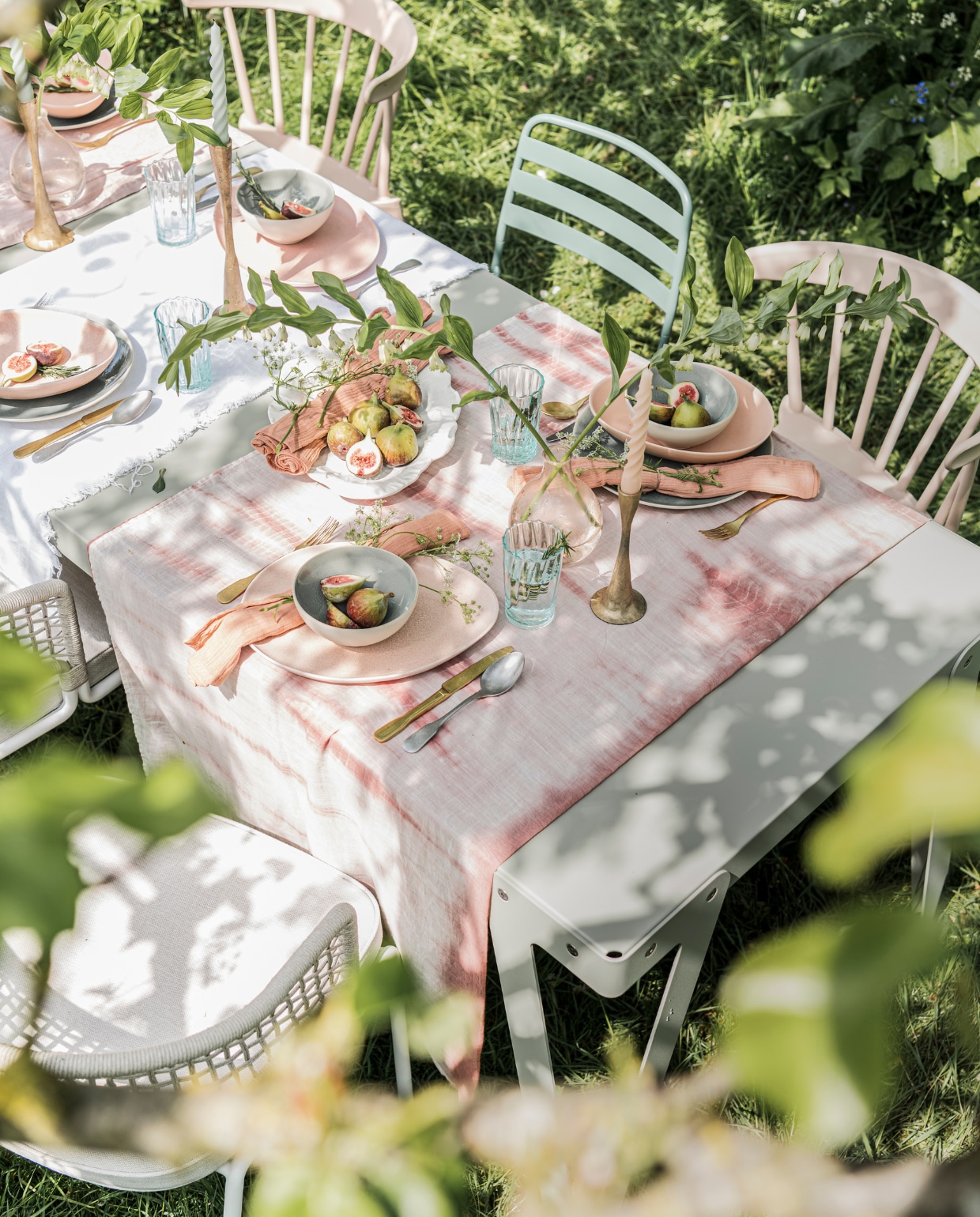 Eettafel Lloyd Outdoor in kleur Parallel Functionals. Buitenstoelen met zitkussen Dacks. Kunststof spijlenstoelen Bliss Basic Label. Groene metalen buitenstoel, roze linnen tafel- kleed H&amp;M Home. Goudkleurige kandelaars, gedraaide kaarsen in verschillende kleuren, stonewashed bestek Paviljoen Noord. Ovale roze borden, ovale roze schalen, turquoise borden, turquoise kommen, Sissy-Boy. Roze servetten Wehkamp. Glazen House Holdware. Tie dye tafelkleed, roze glazen vaasjes Weldaad. Witte schaal in bloemvorm Arket. vtwonen 08-2021 | styling Danielle Verheul | fotografie Sjoerd Eickmans
