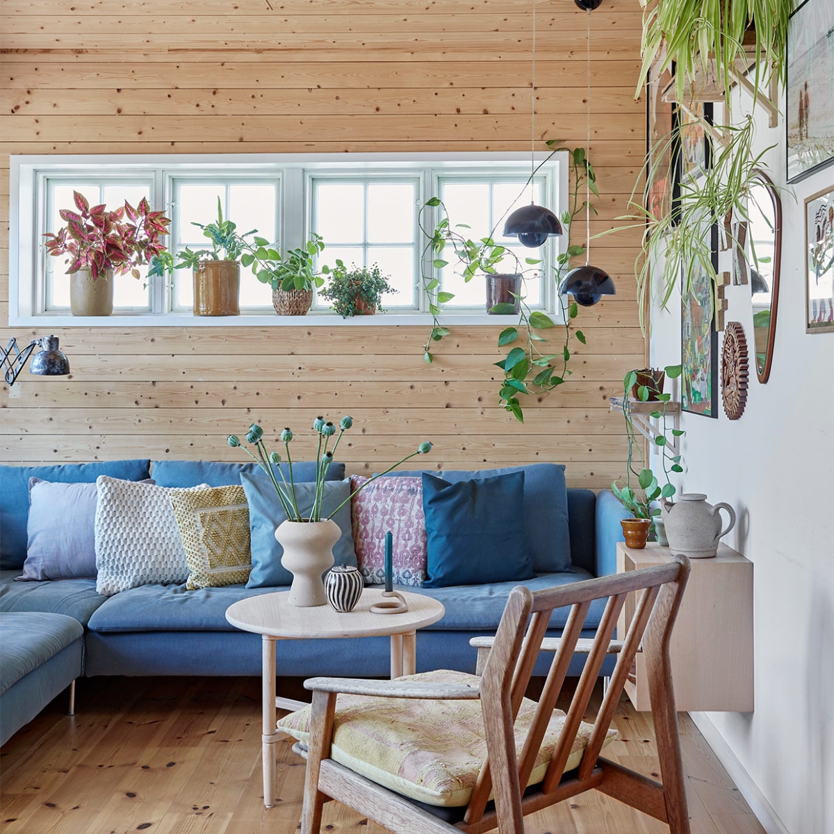 Blauwe bank Ikea. Kussens Au Maison en Madam Stoltz. Stoel en stoelkussen erfstukken. Ronde salontafel en hangend kastje DBA (Deense eBay). Beige vaas Ilva. Zwart-witte vaas, theepot en spiegel kringloop. Kandelaar Anthropologie. Wandlamp Leben CPH. Bloempotten voor het raam erfstukken en kringloopvondsten. Hanglampen Flowerpot &amp;Tradition. Aan de muur foto’s van reizen en kunst van een galerie in Ebeltoft. Wandplank zelfgemaakt. Overig onbekend. vtwonen special zomerhuizen 07-2021 | productie LIVING INSIDE | fotografie Anitta Behrendt | styling Rikke Graff Juel