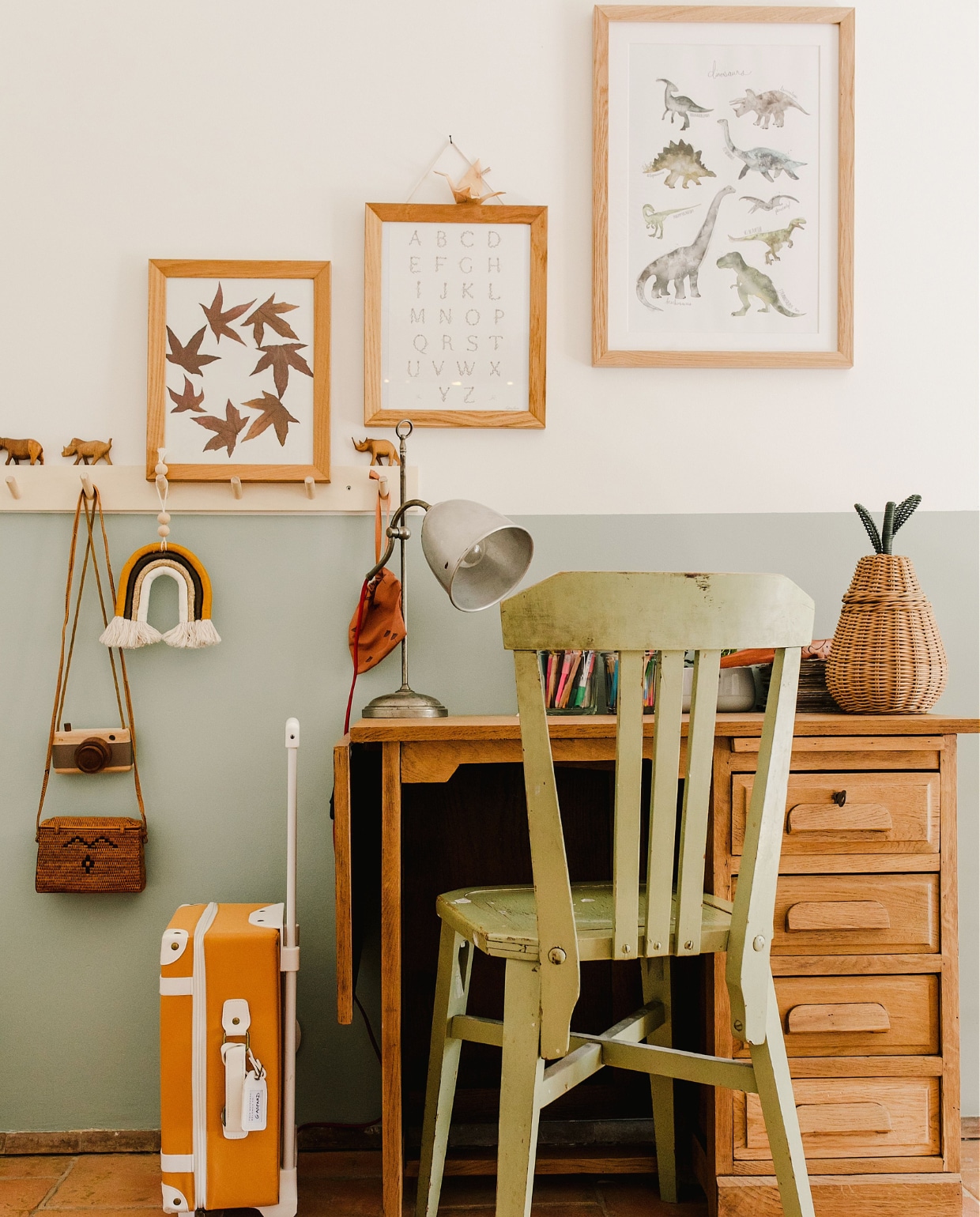 Muurverf Green Blue van Farrow &amp; Ball. Schoolbureau vintage vondst. Lamp en stoel uit de familie. Koffertje Olli Ella. Print dinosaurus Juniqe, overige zelf-gemaakt. vtwonen special binnenkijken 171-2022 | productie The Sisters Agency | styling fotografie en brontekst Marta Puglia | tekstbewerking Monique van der Pauw