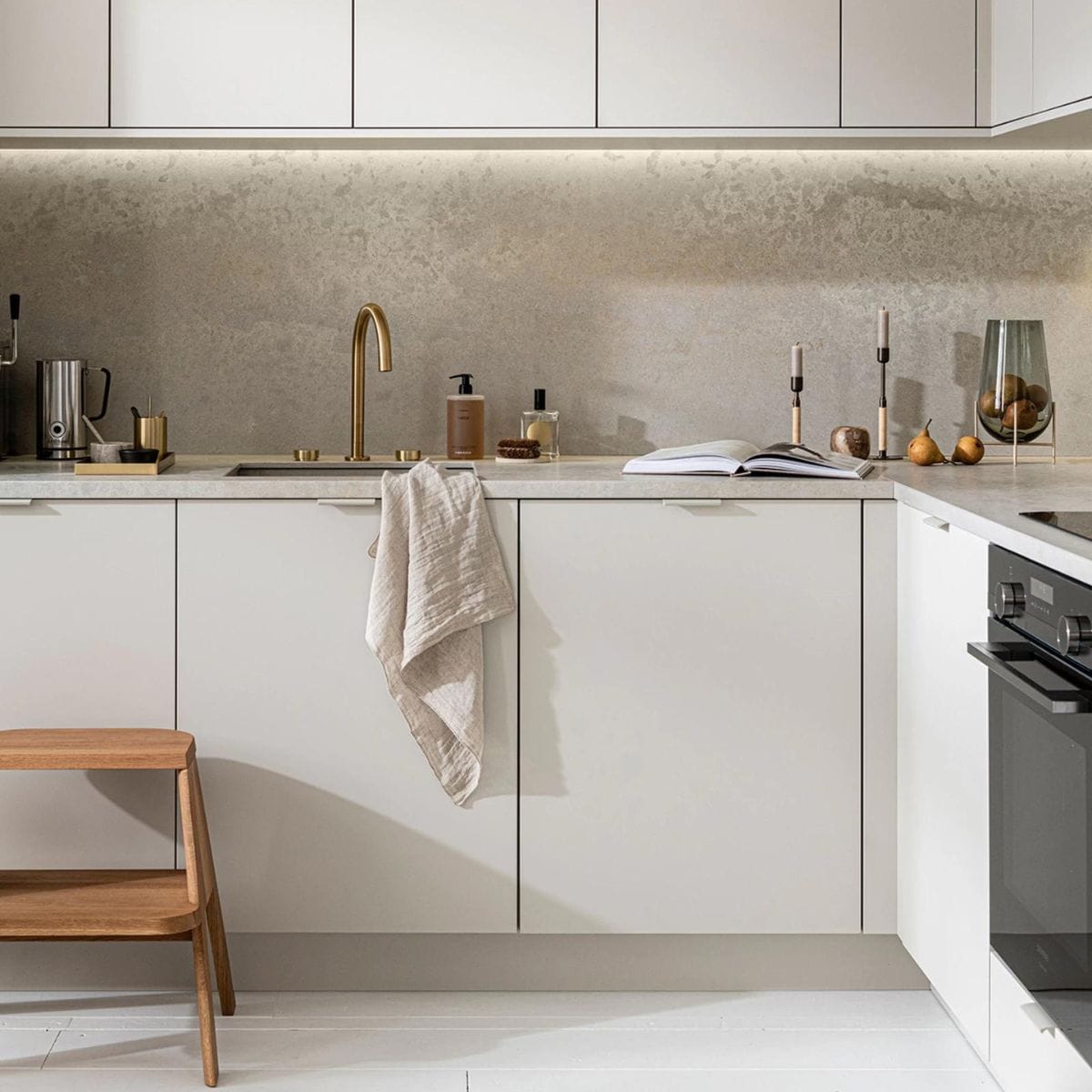 Keuken Basic Greige, vanaf € 21.500,-, M.m.v. thefinestore.com (houten krukje van Hay, messing dienblad en beker van Ferm Living, bronzed brass kandelaren Duca van Menu), flinders.nl (vaas van gerookt glas op messing pootjes van Menu), kikubari.nl (spray van Lingua Planta), vtwonen.nl (theedoek uit de vtwonen collectie), skins.nl (handzeep Suede Byredo), sjostrandcoffee.nl (melkschuimer). Overig privébezit. vtwonen 03-2021 | productie Tanja Saarberg | styling Kim van Rossenberg | fotografie Sjoerd Eickmans